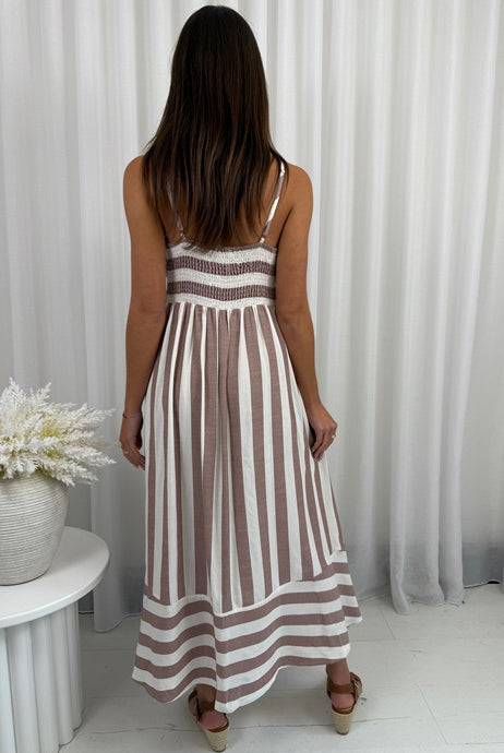 Woman wearing a striped dress standing in front of white curtains