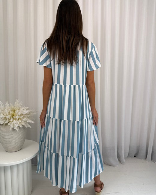 Woman wearing a blue and white striped dress against a neutral background