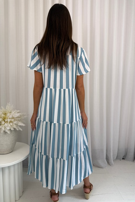 Woman wearing a blue and white striped dress against a neutral background