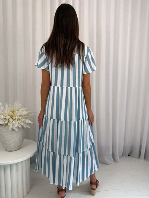 Woman wearing a blue and white striped dress against a neutral background
