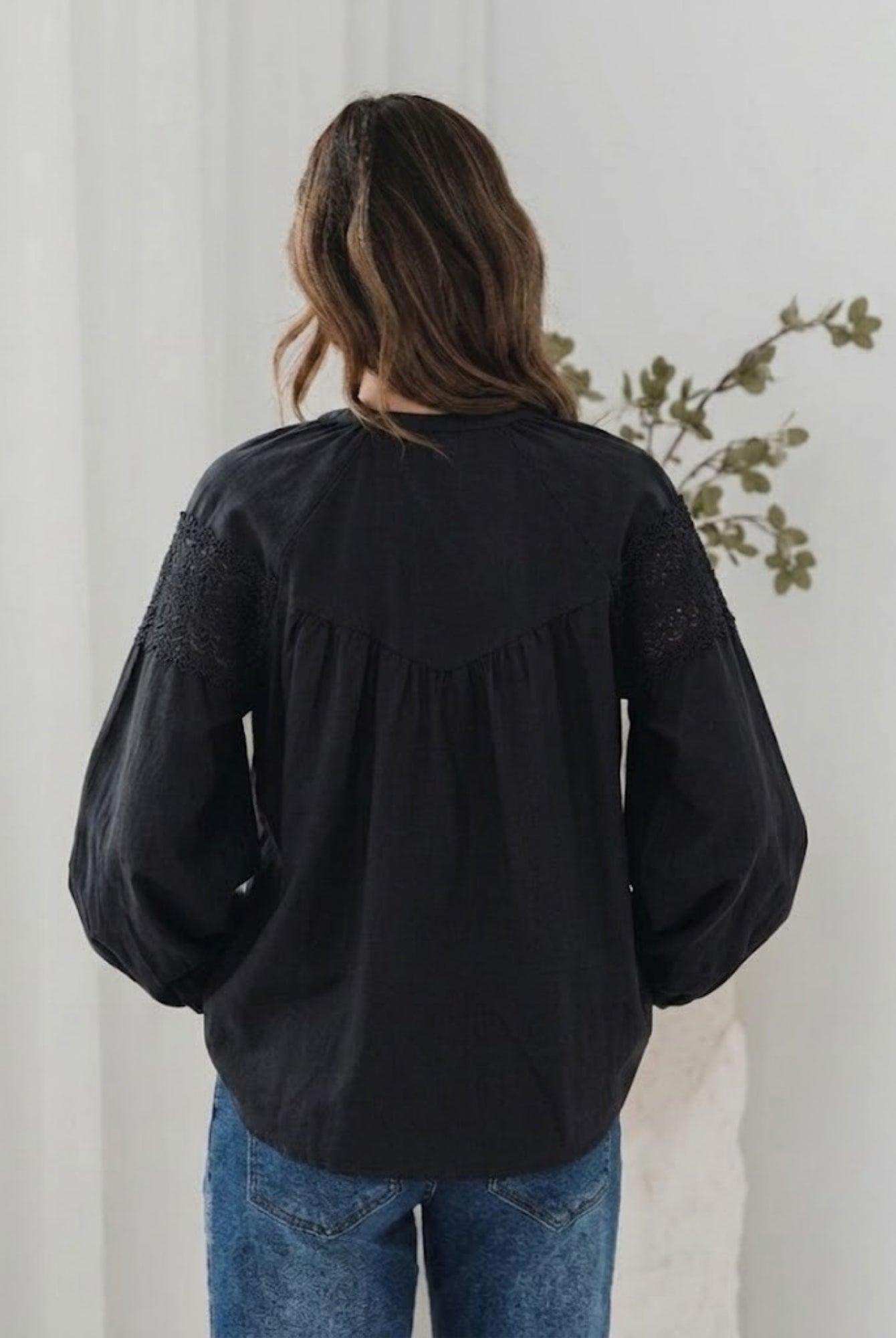 Women's black lace blouse with fabric tie detail styled with denim by Esther & Co