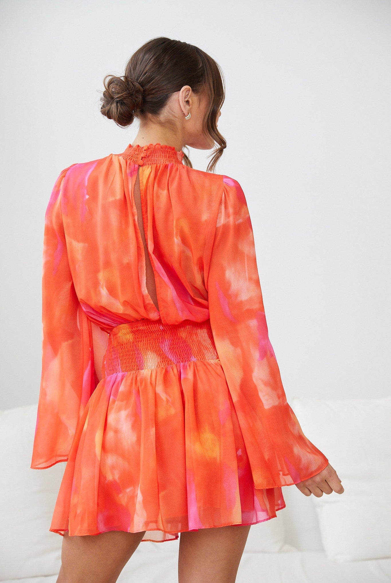 Front view of the Daenerys Mini Dress in Orange Print showing the smocked bodice and high neck detail