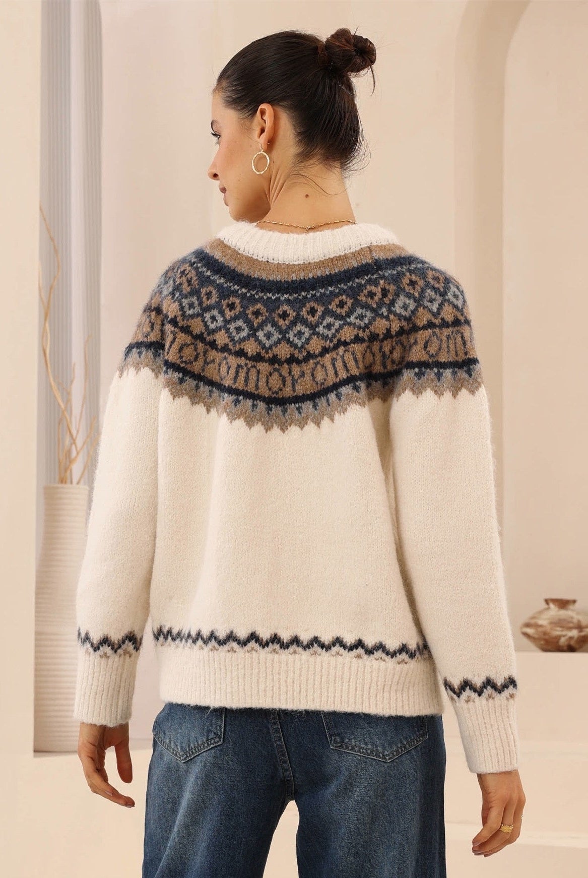 Woman wearing a patterned sweater with a neutral background