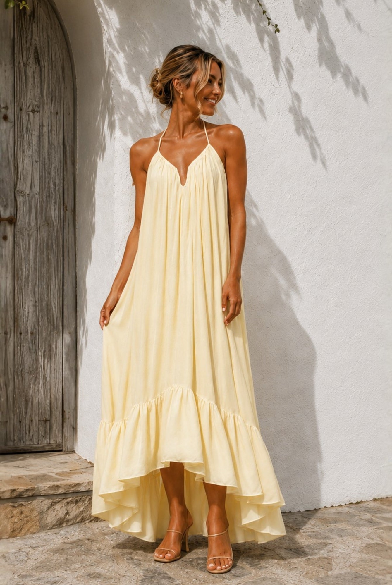 Women's pastel yellow halter neck high low dress full length view, the Flynne Dress in Sunrise Glow by Esther & Co