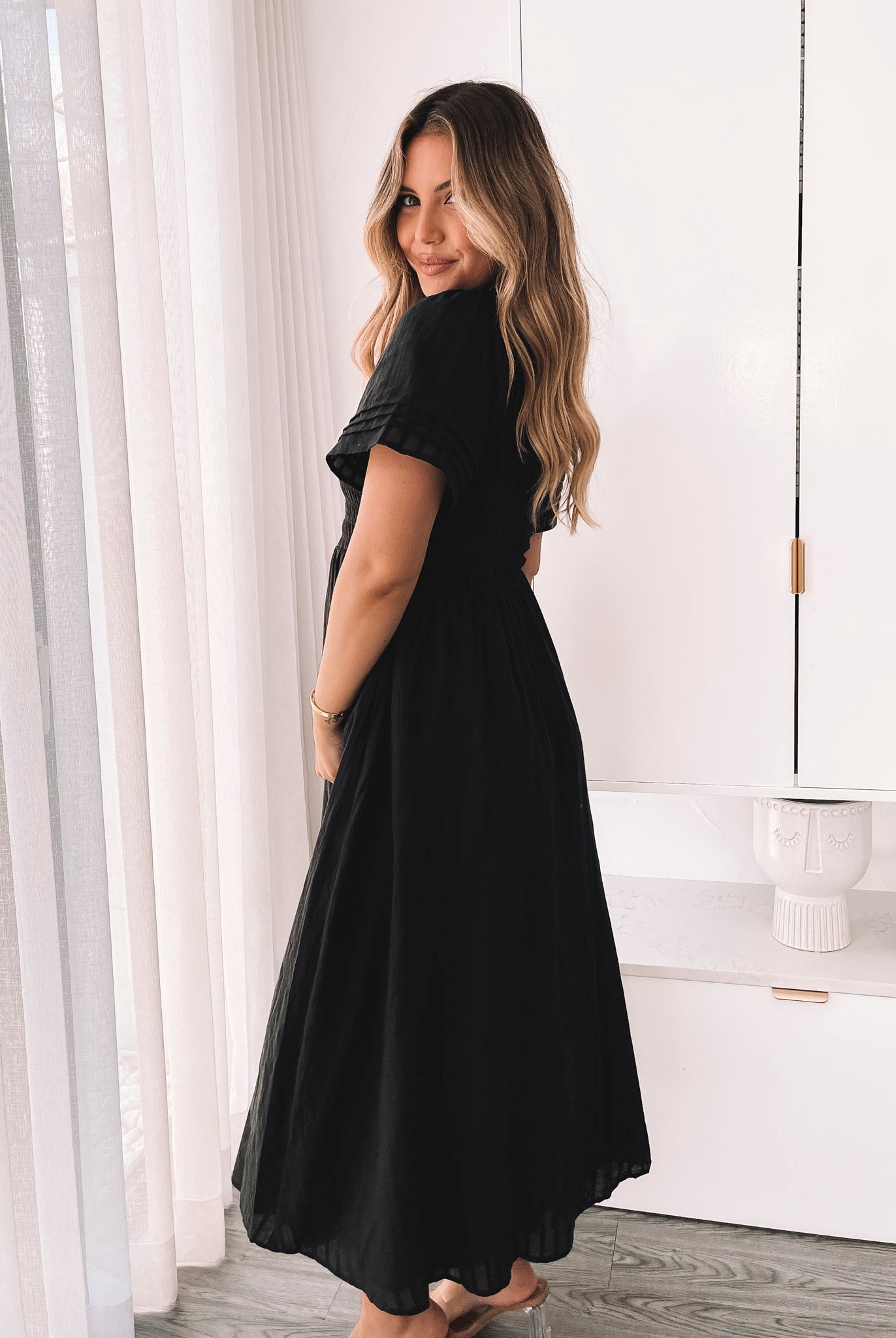 Side view of the Iolana Dress in Black showing the flowing A-line skirt and short sleeves