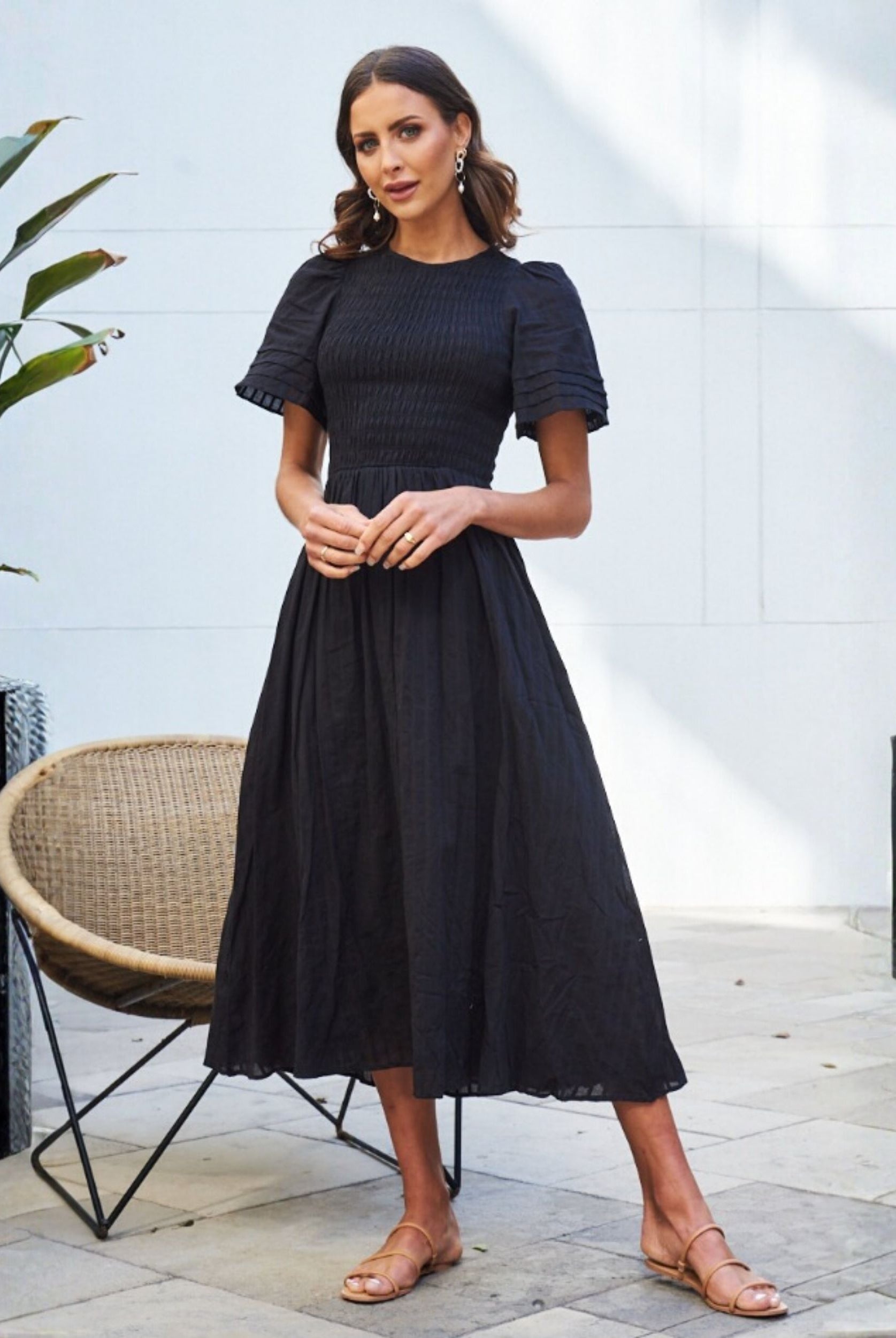 Women wearing the Iolana Dress in Black, a flattering cotton smock midi dress with round neckline and short sleeves