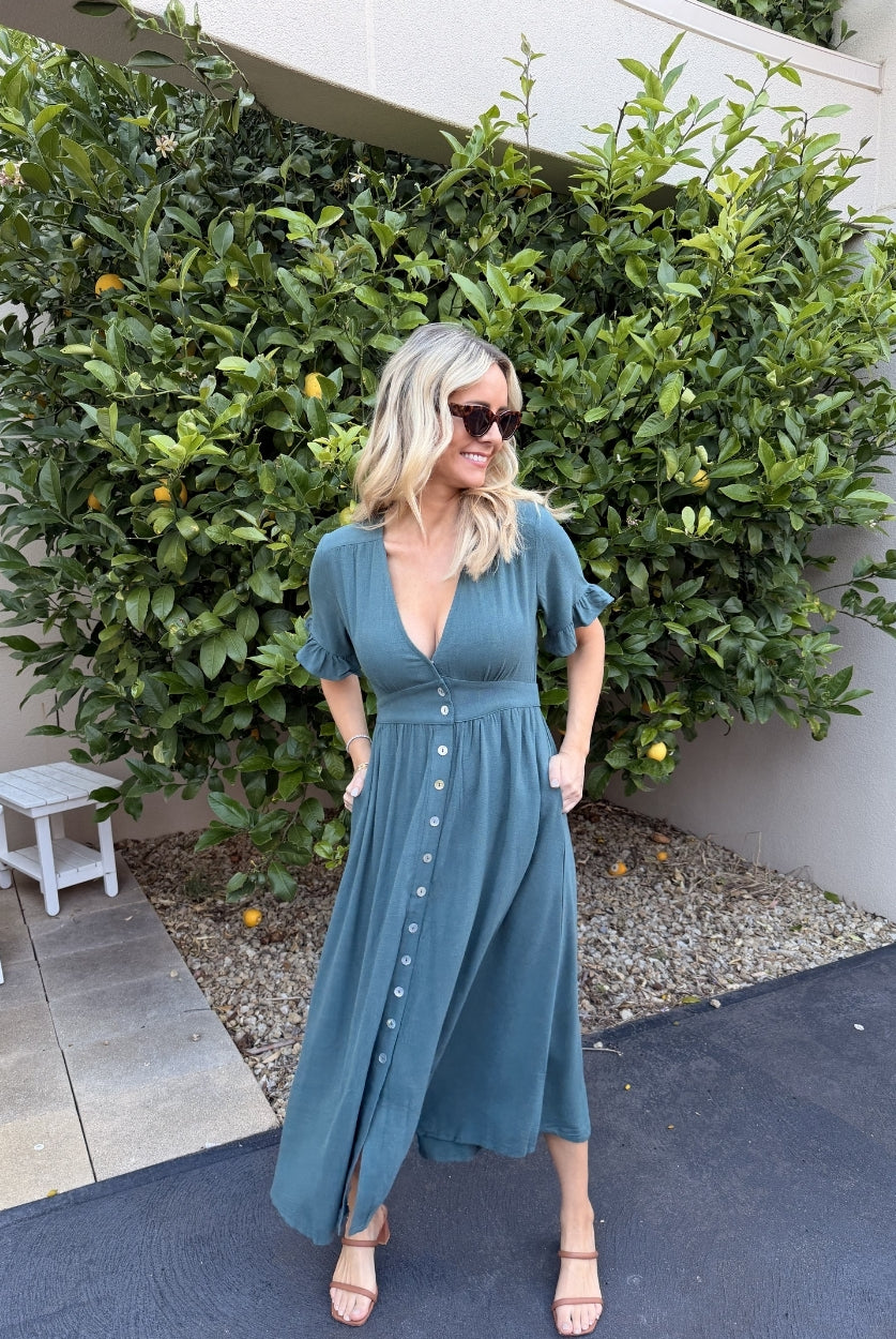 Model wearing the Korbela Deep Green Midi Dress styled with tan sandals for a casual summer look