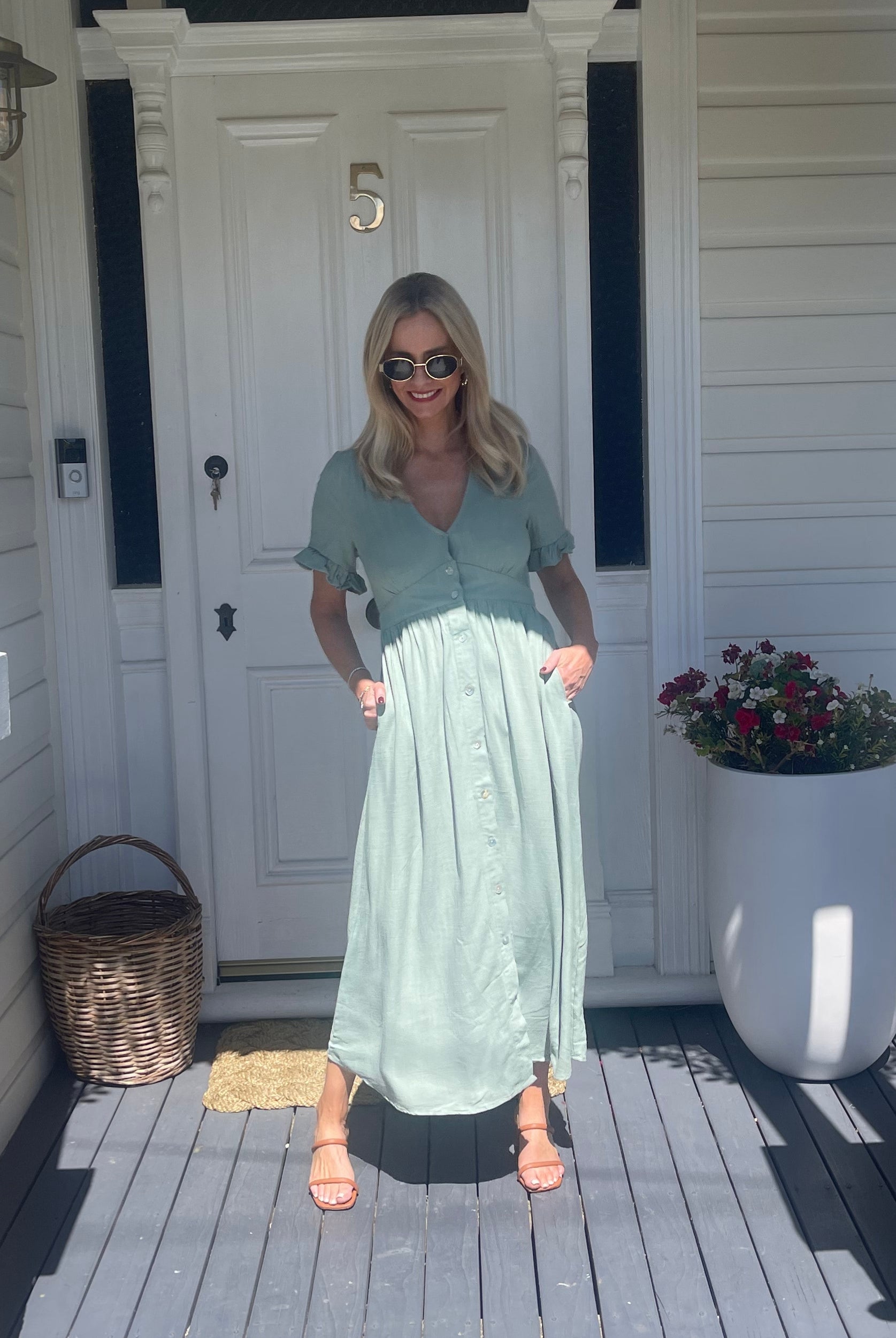 Model wearing the Korbela Sage Midi Dress with sandals and straw bag for a holiday look