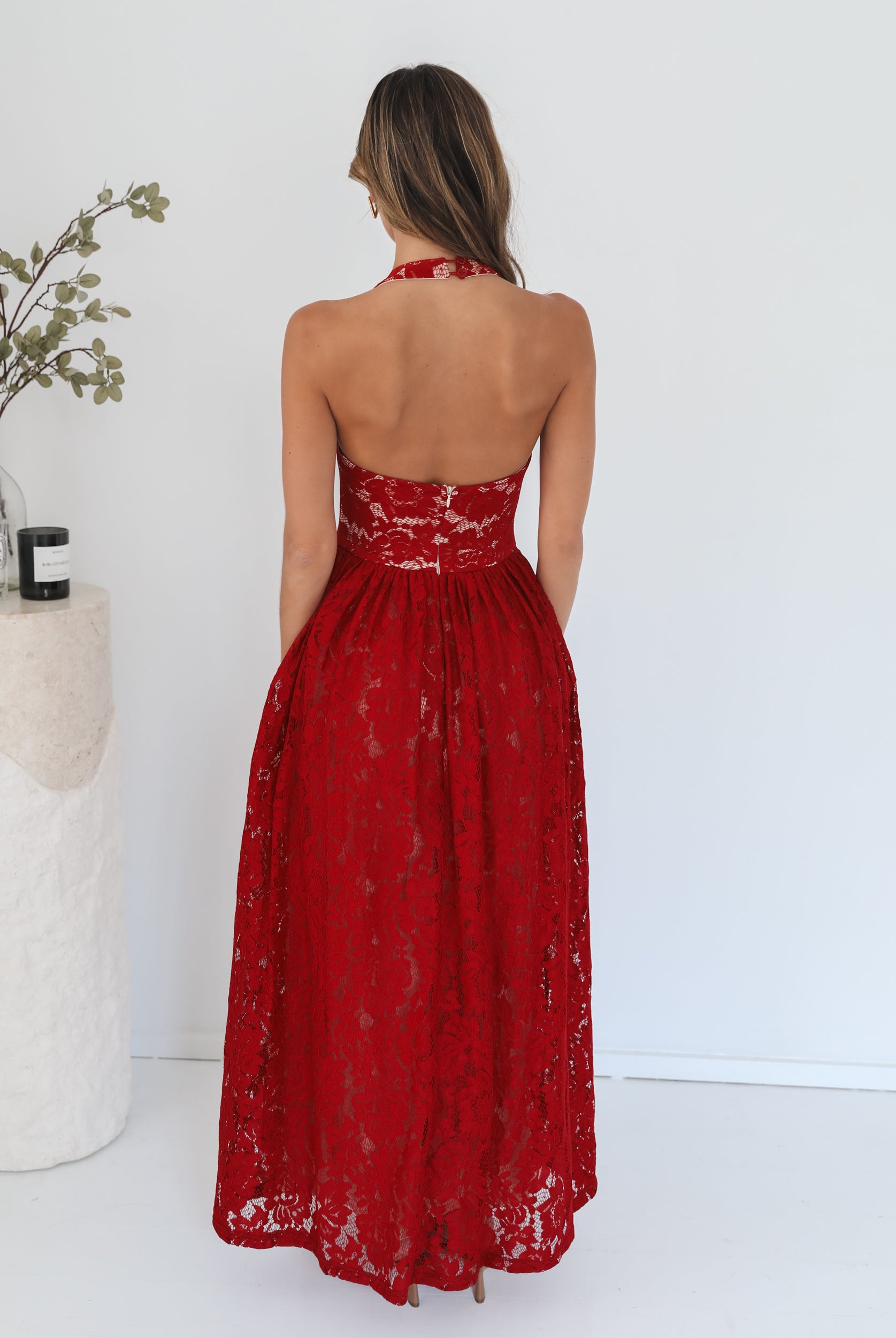 A woman wearing a red maxi dress with a halter neckline.