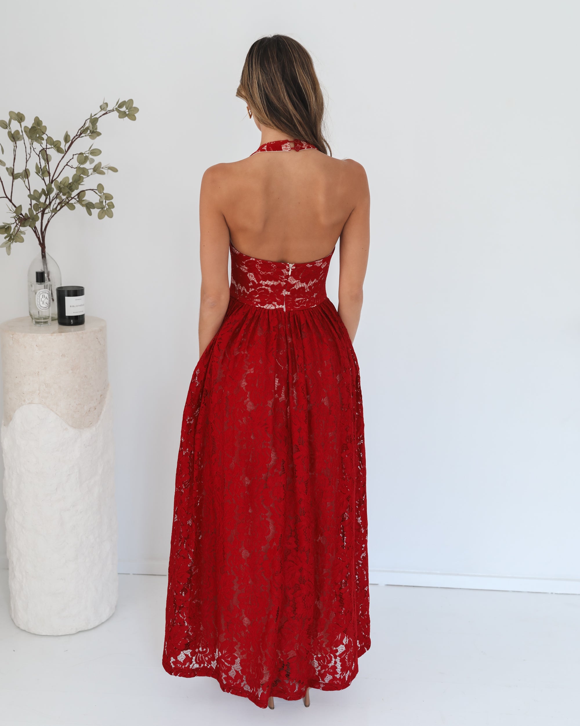 A woman wearing a red maxi dress with a halter neckline.