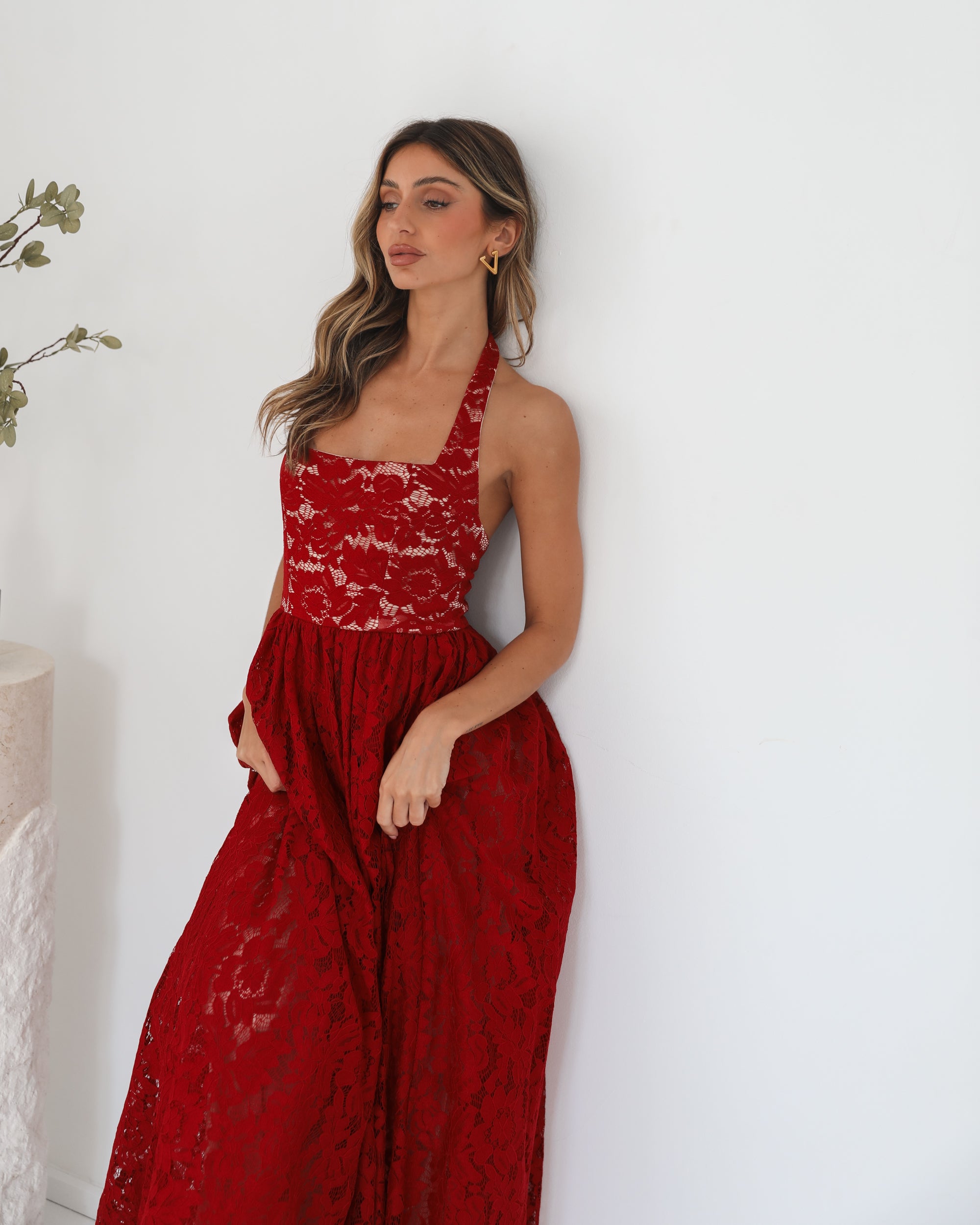 A woman wearing a red maxi dress with a halter neckline.