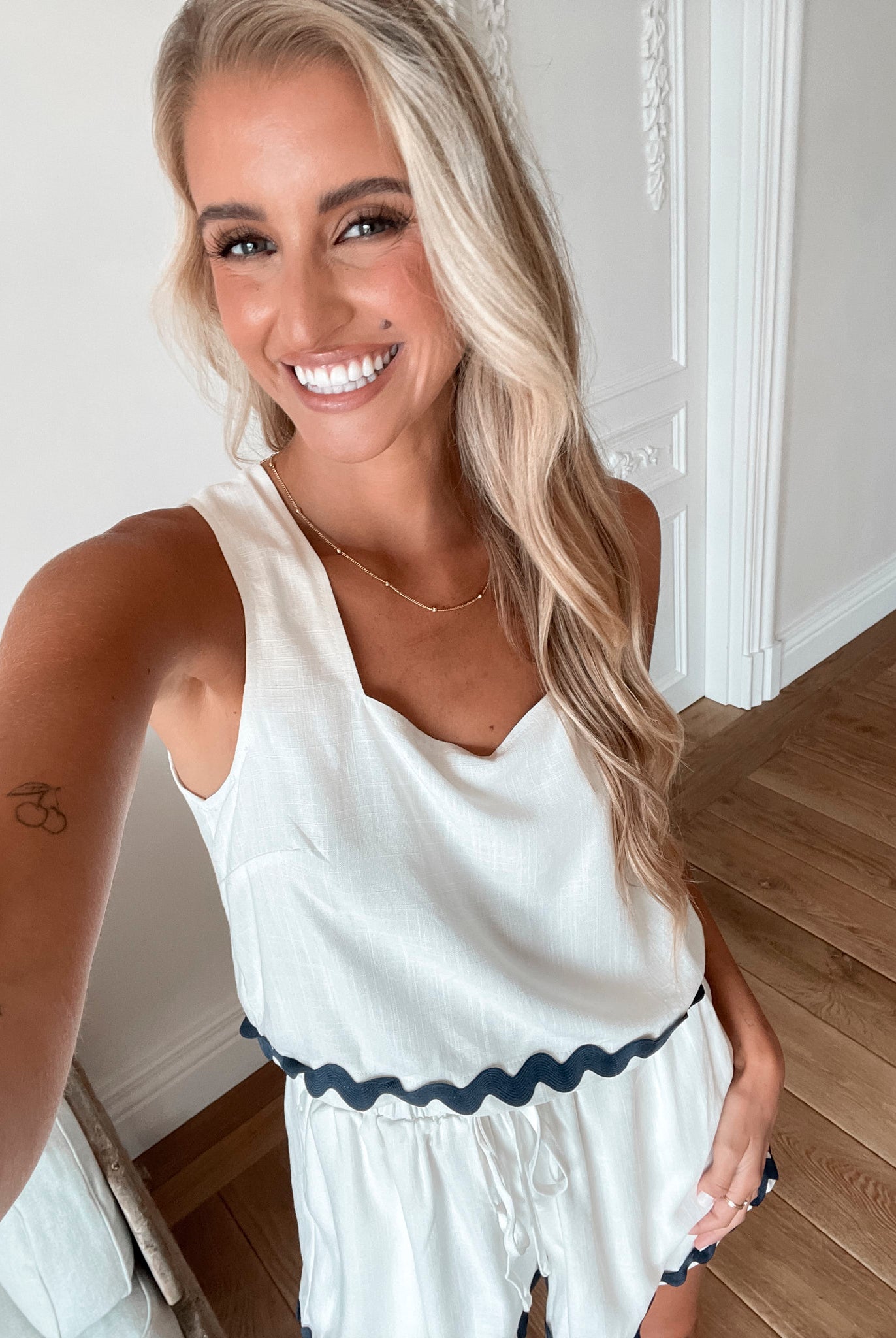 A woman wearing a white crop top with a square neckline and semi-relaxed fit, in a room with classic decor.