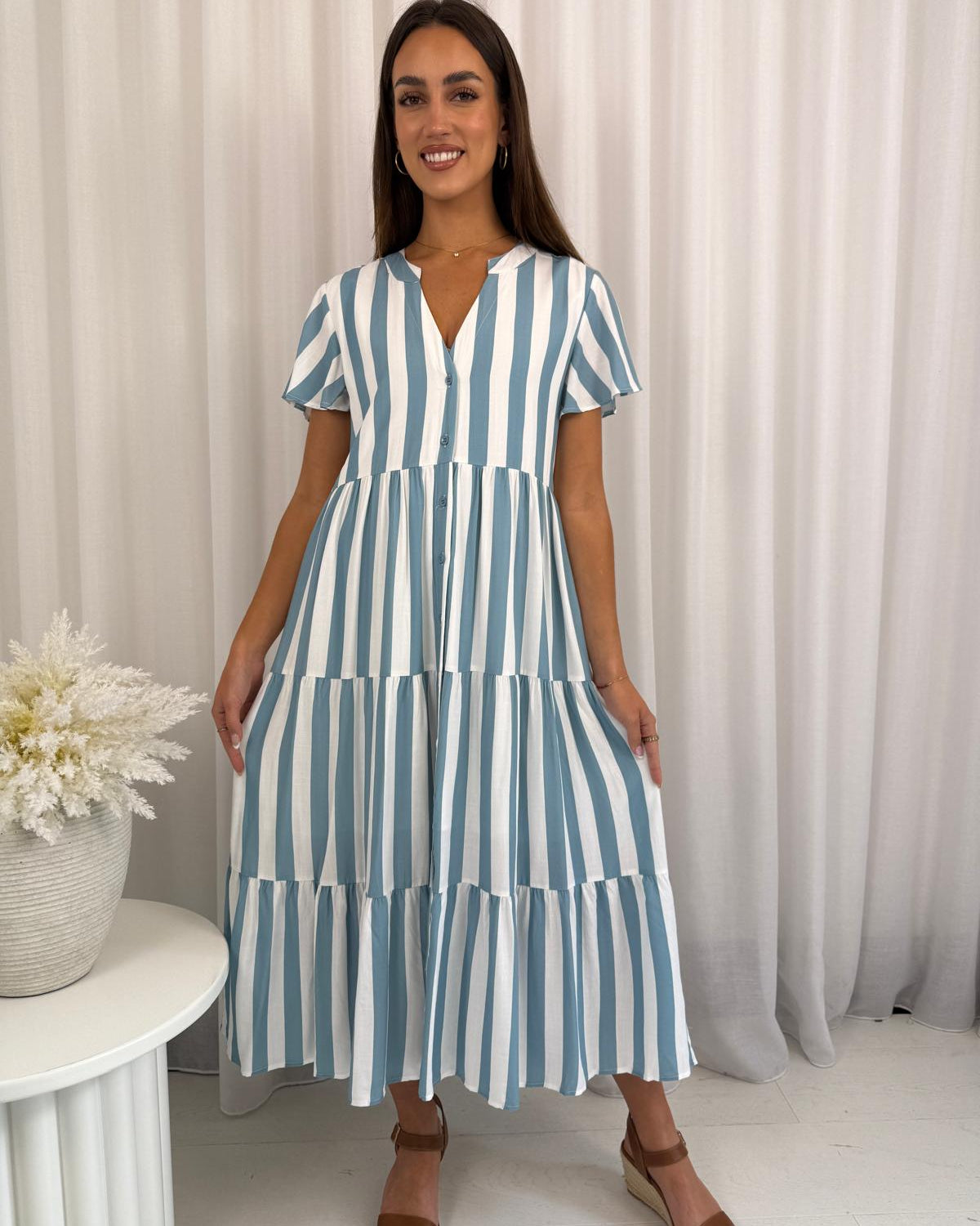 Woman wearing a blue and white striped dress against a neutral background