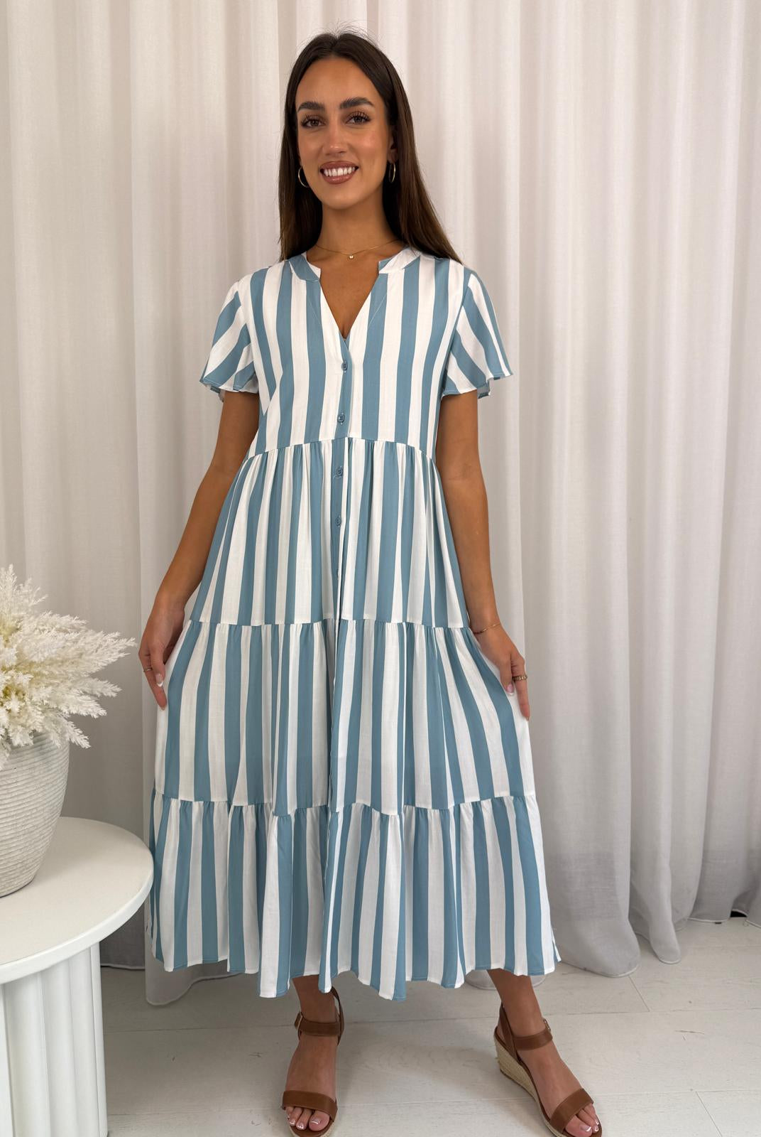 Woman wearing a blue and white striped dress against a neutral background