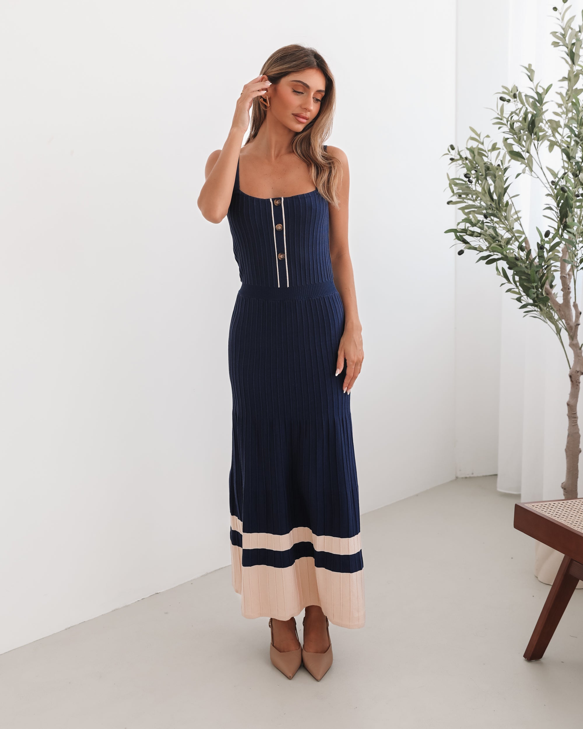 A navy and beige toned dress with thin straps and a square neckline. The dress has a fit-and-flare silhouette and reaches mid-calf in length.