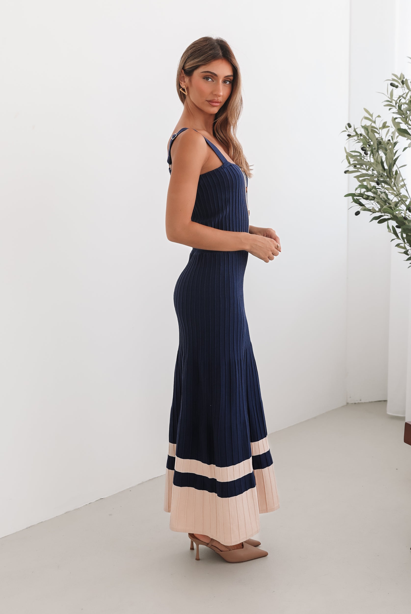 A navy and beige toned dress with thin straps and a square neckline. The dress has a fit-and-flare silhouette and reaches mid-calf in length.