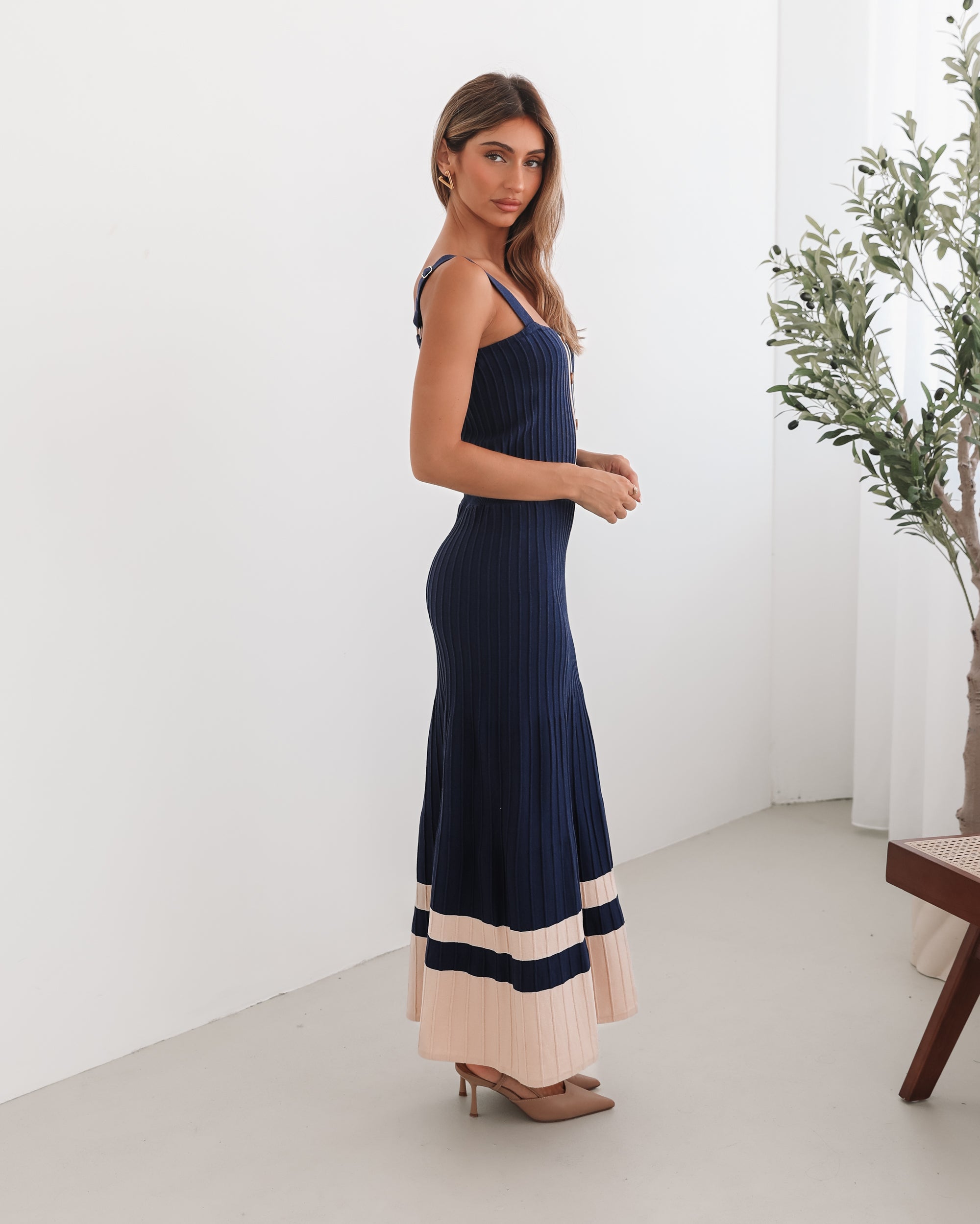 A navy and beige toned dress with thin straps and a square neckline. The dress has a fit-and-flare silhouette and reaches mid-calf in length.