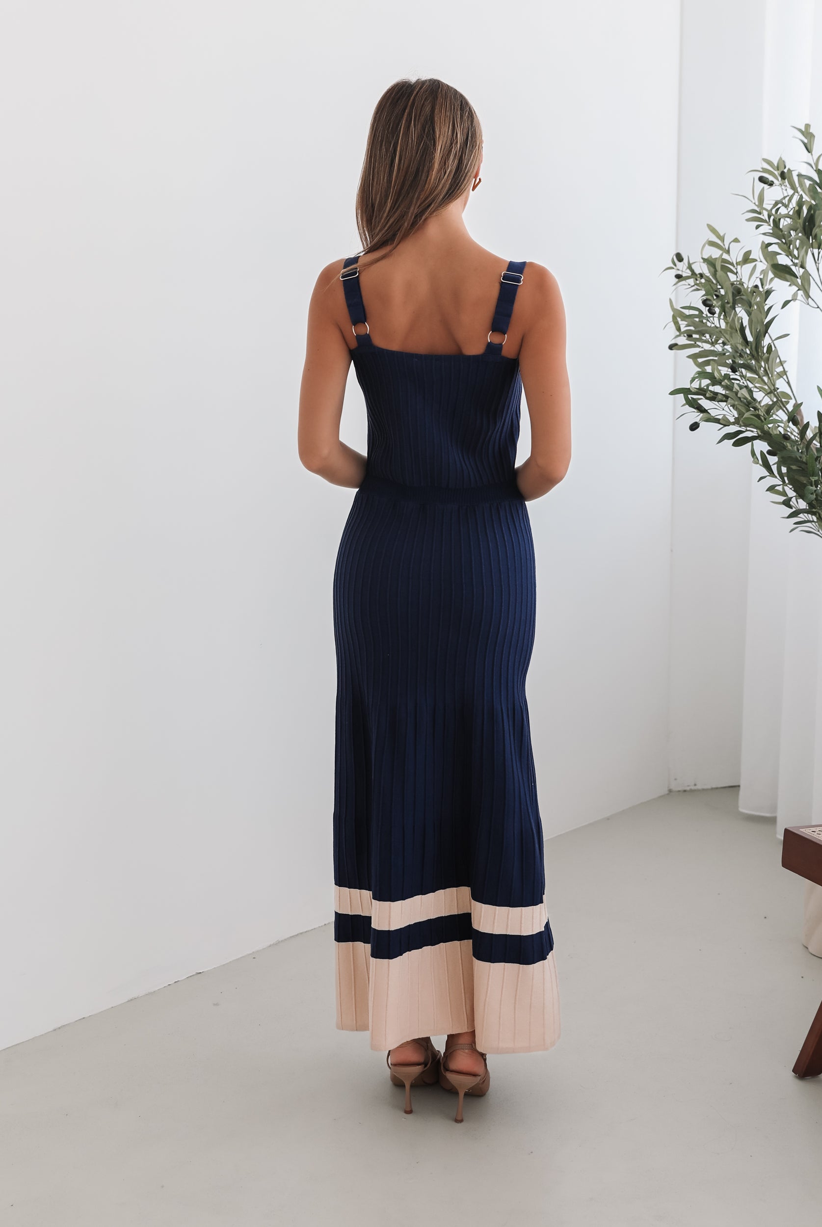A navy and beige toned dress with thin straps and a square neckline. The dress has a fit-and-flare silhouette and reaches mid-calf in length.