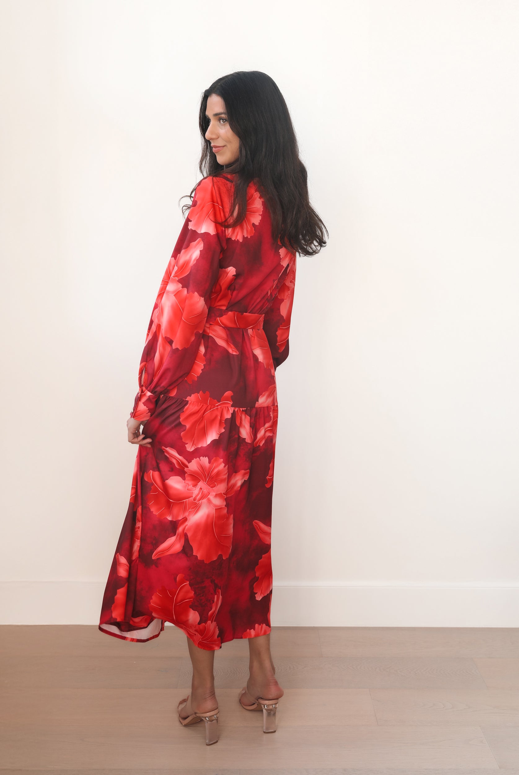 Woman wearing a red floral dress against a white background