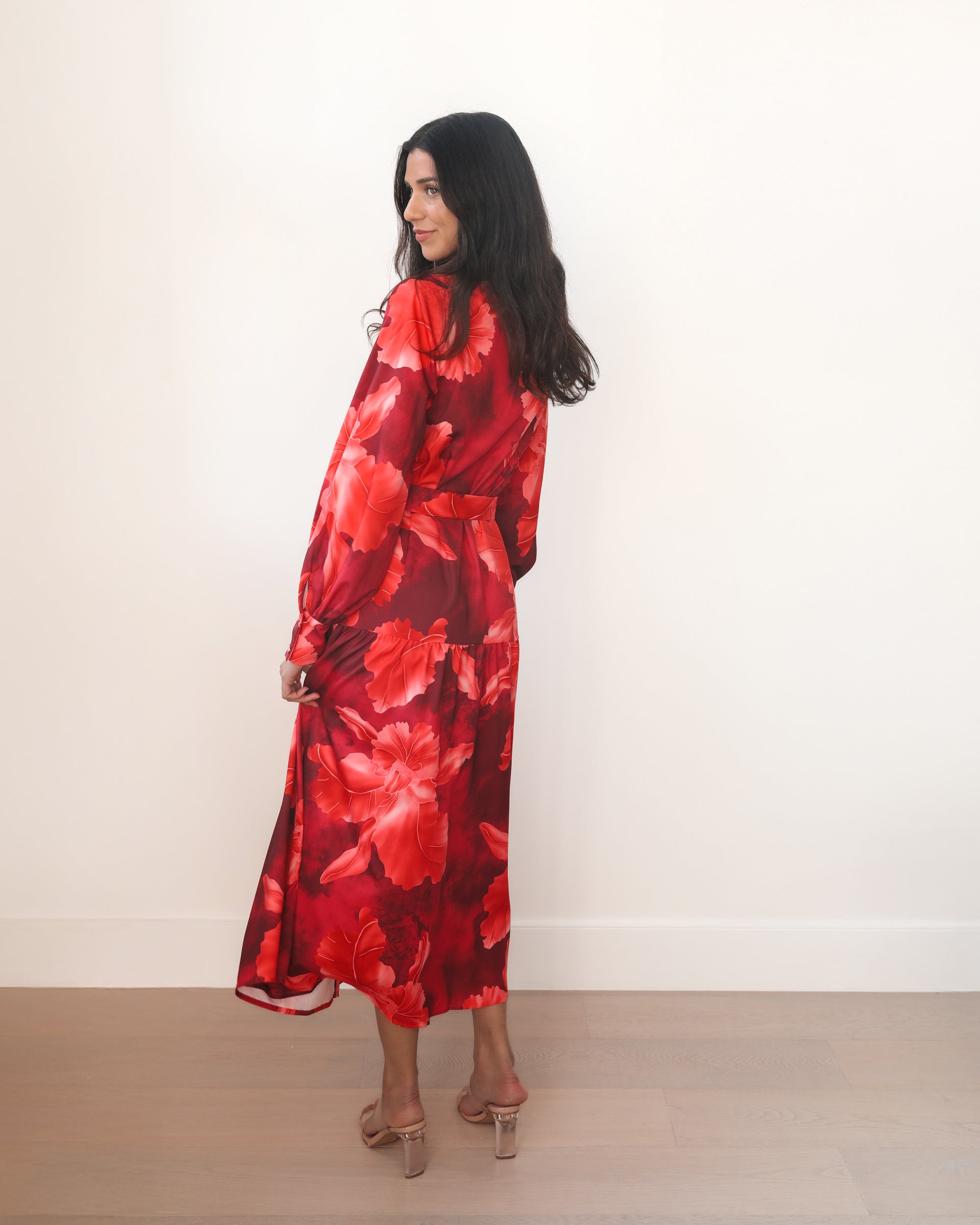 Woman wearing a red floral dress against a white background