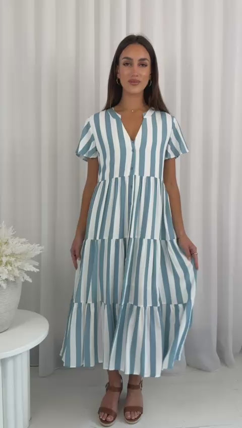 Woman wearing a blue and white striped dress against a neutral background