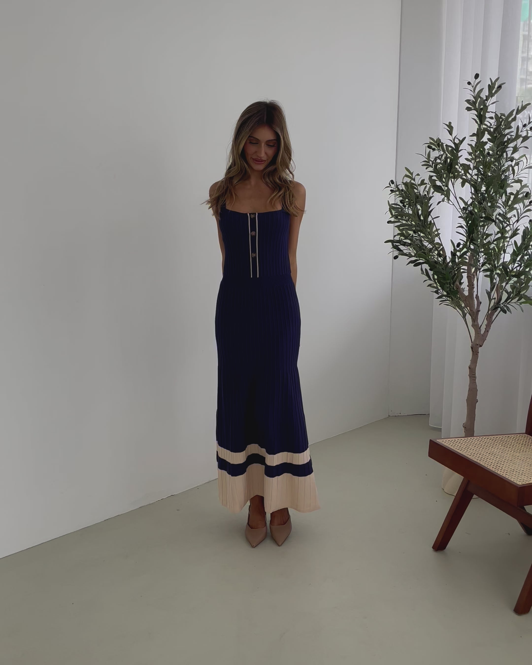 A navy and beige toned dress with thin straps and a square neckline. The dress has a fit-and-flare silhouette and reaches mid-calf in length.