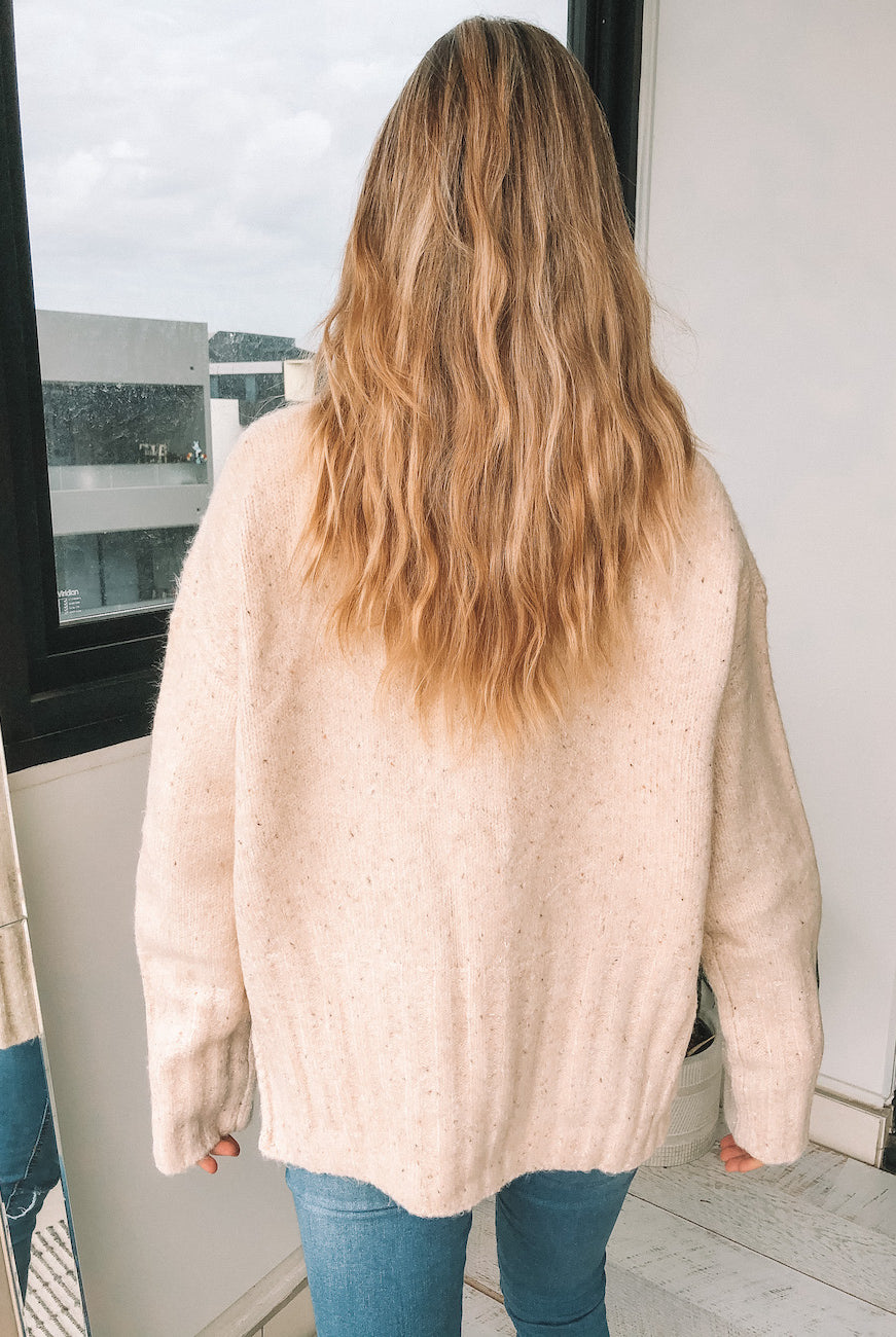 Side view of the Chesterfield Jumper in Beige showing the textured mocha speckle knit fabric