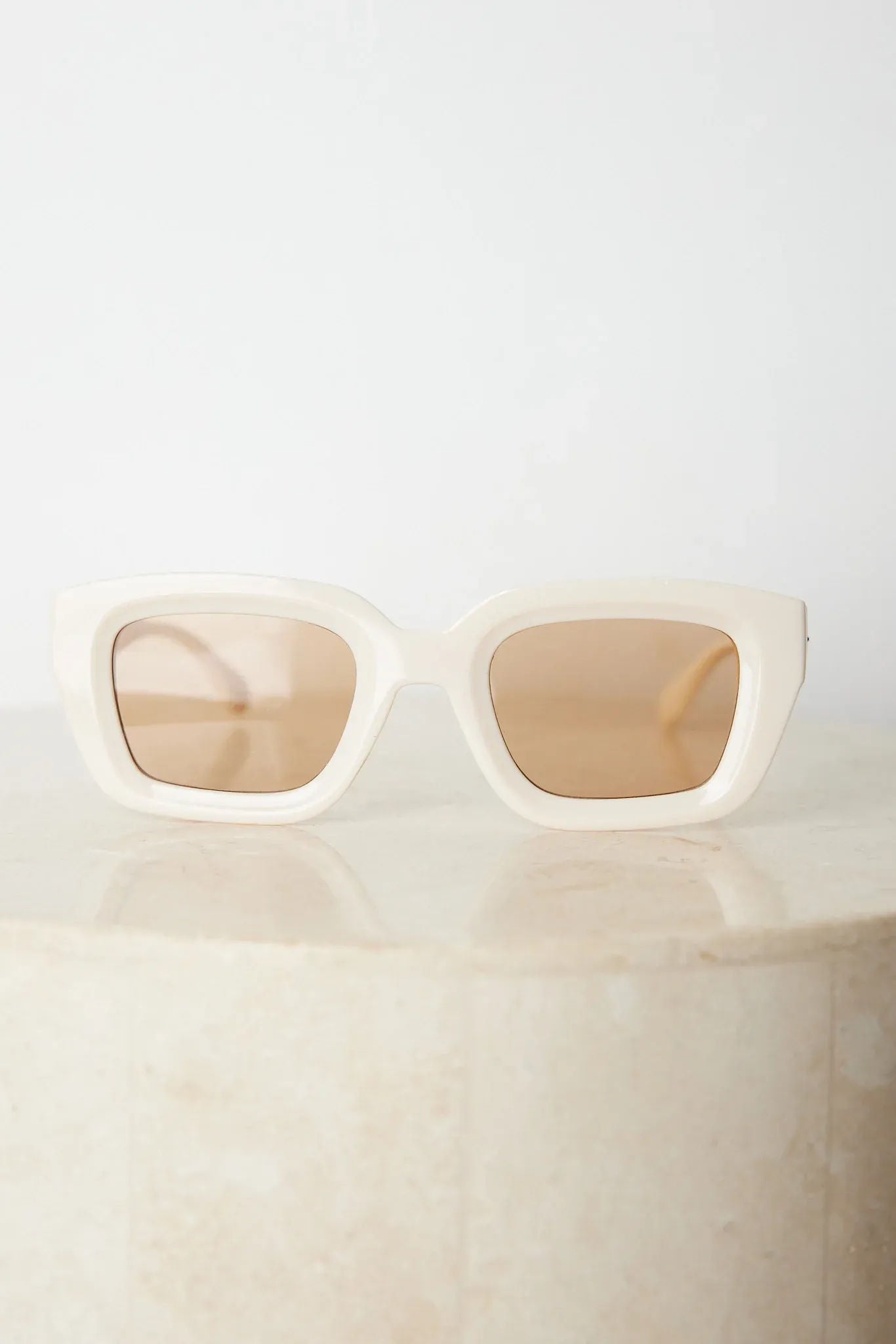 A pair of beige sunglasses displayed on a surface.