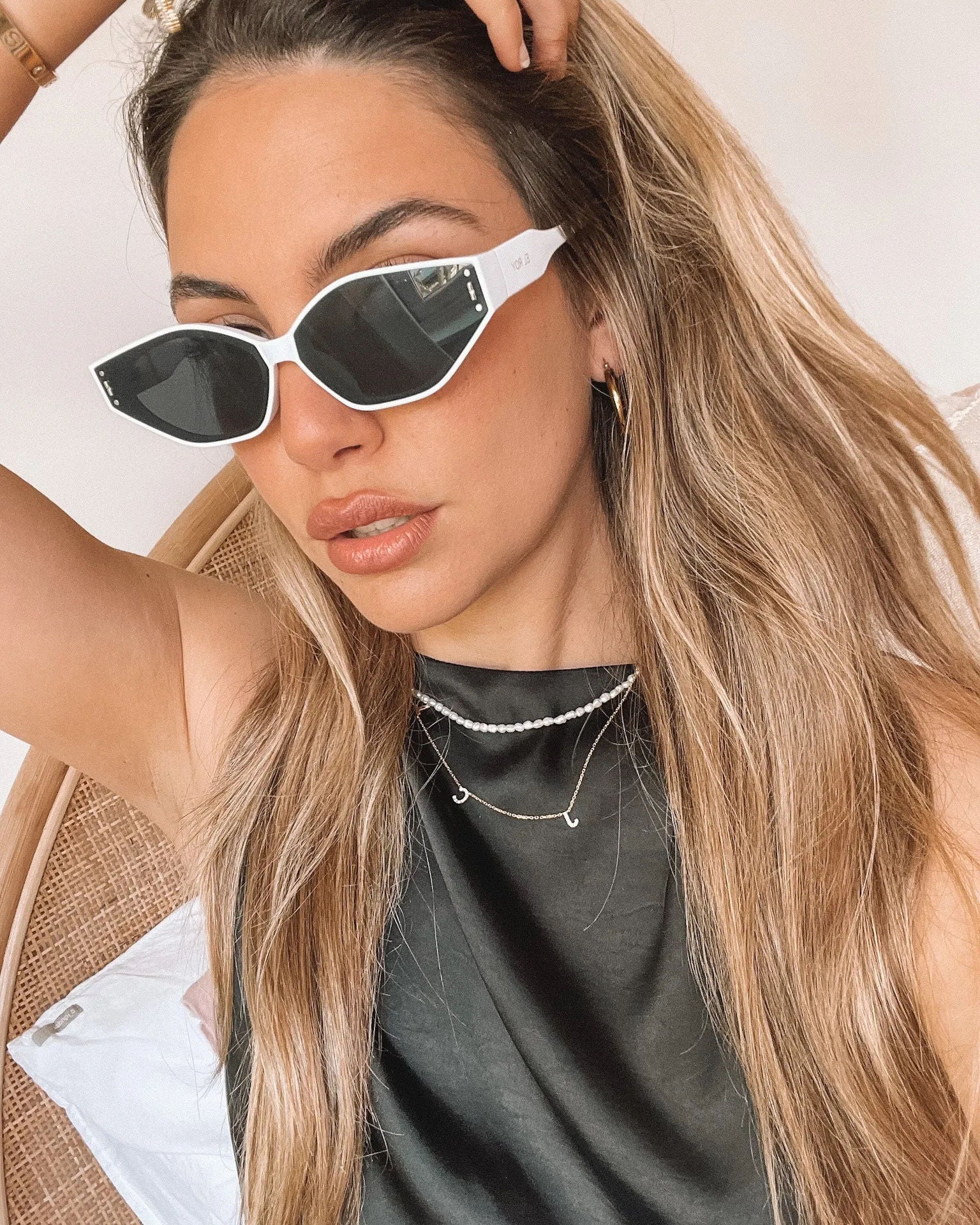 White geometric-shaped sunglasses with dark lenses resting on a light marble surface against a plain white background.