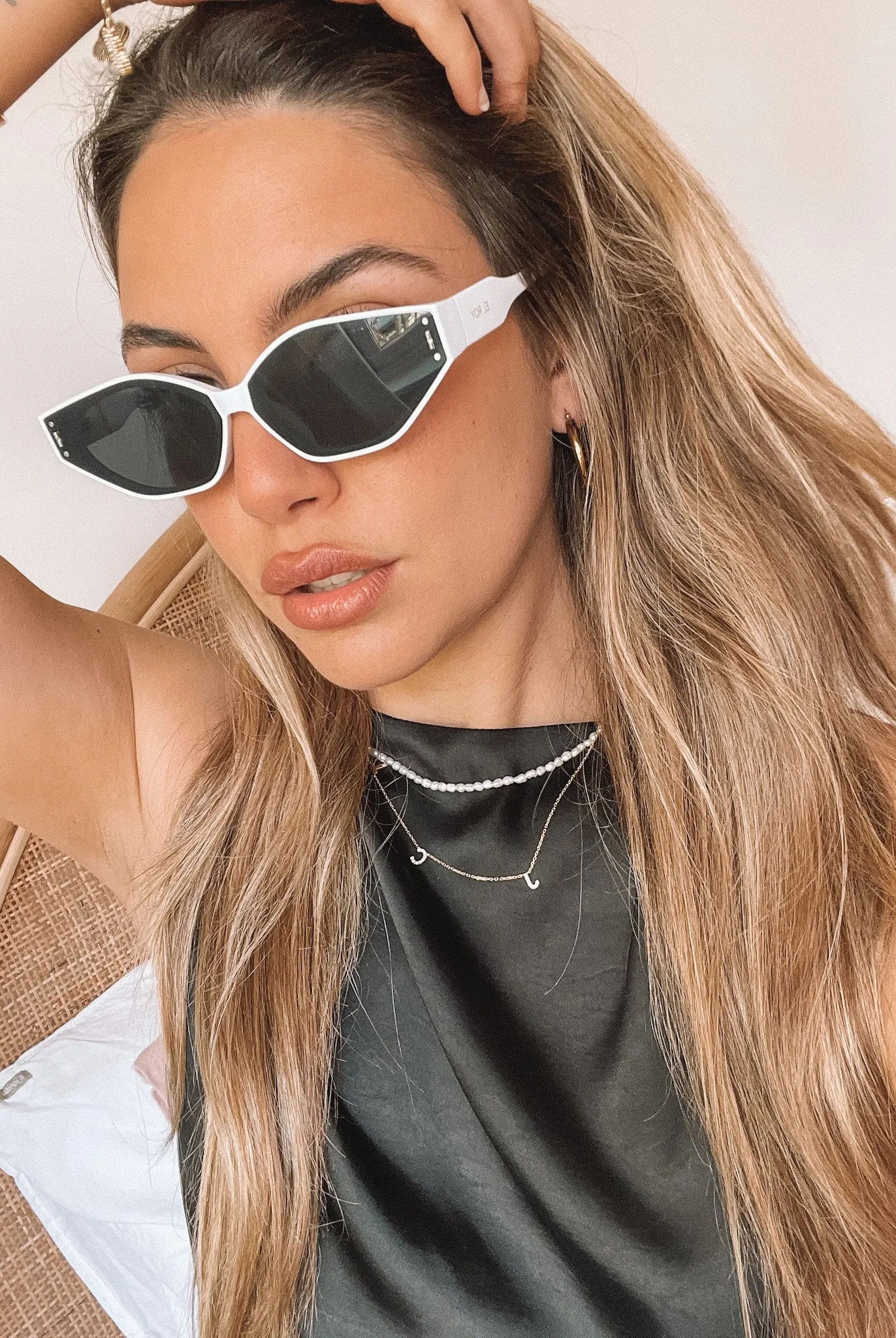 White geometric-shaped sunglasses with dark lenses resting on a light marble surface against a plain white background.
