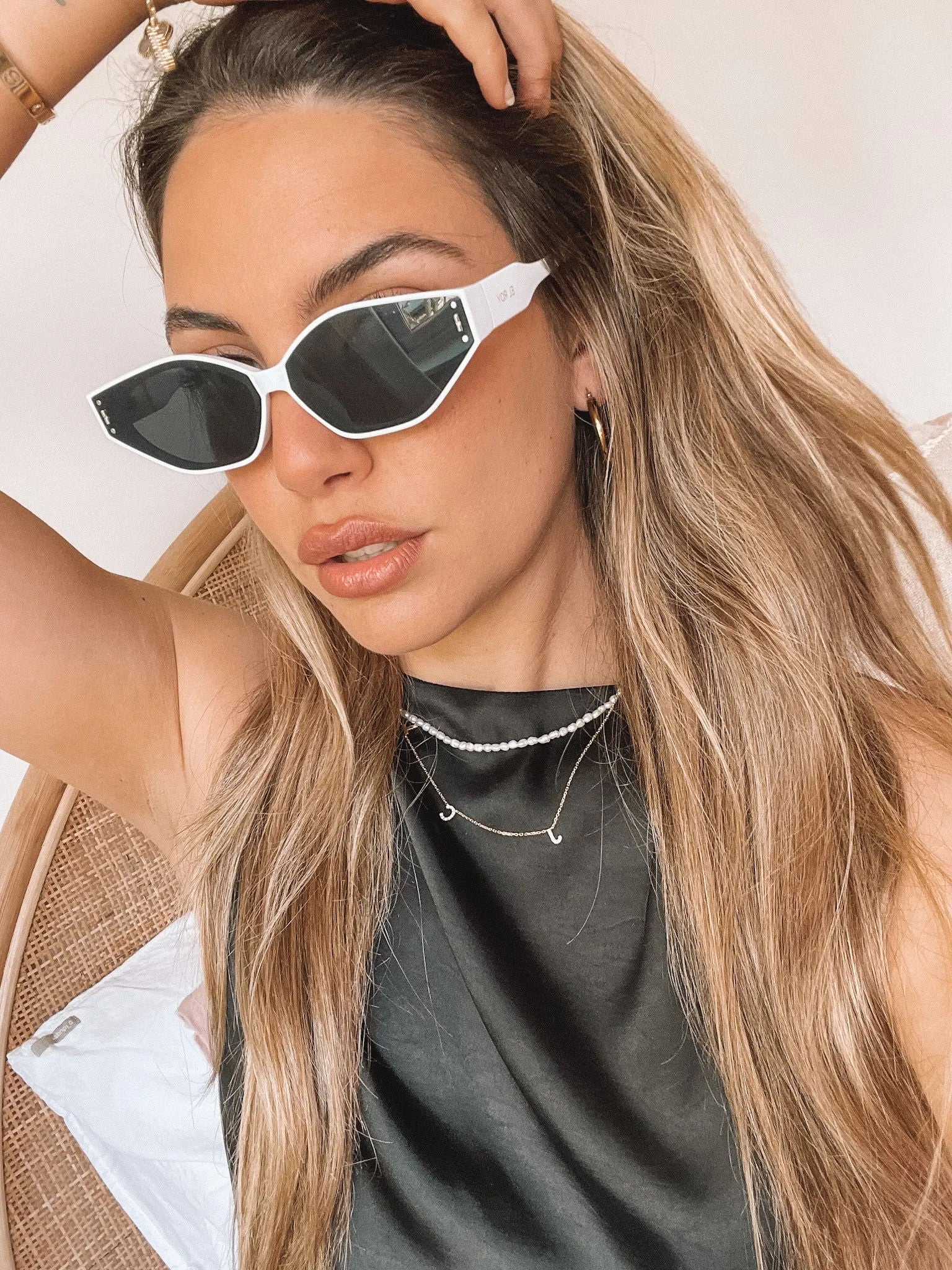 White geometric-shaped sunglasses with dark lenses resting on a light marble surface against a plain white background.