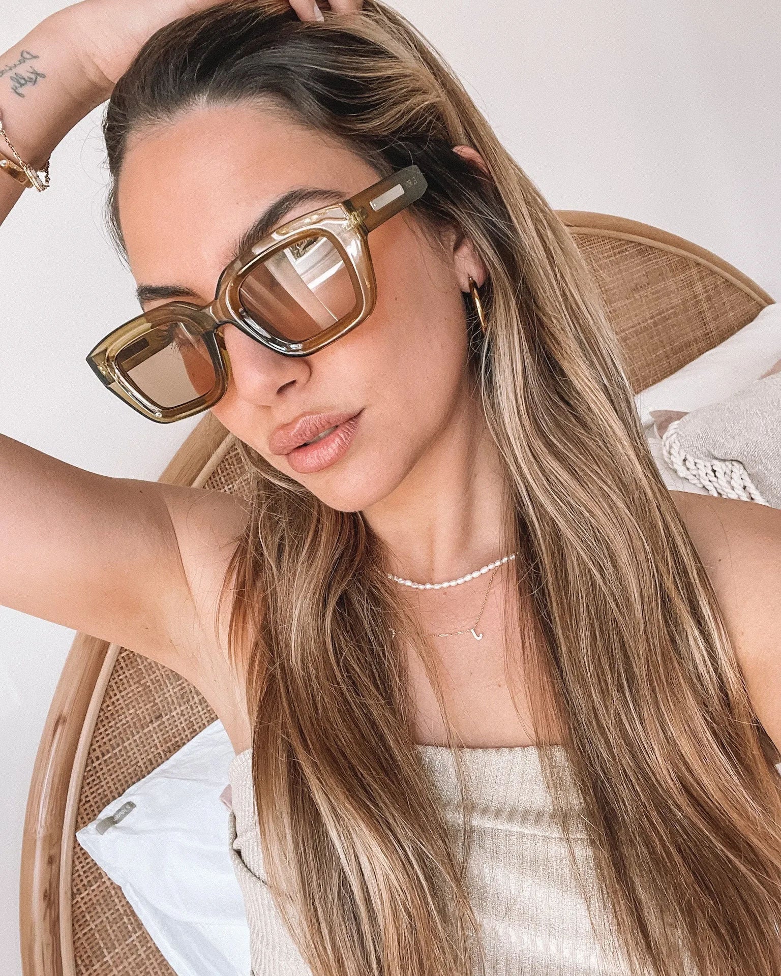 A pair of sunglasses with olive green frames and pink lenses displayed on a surface.