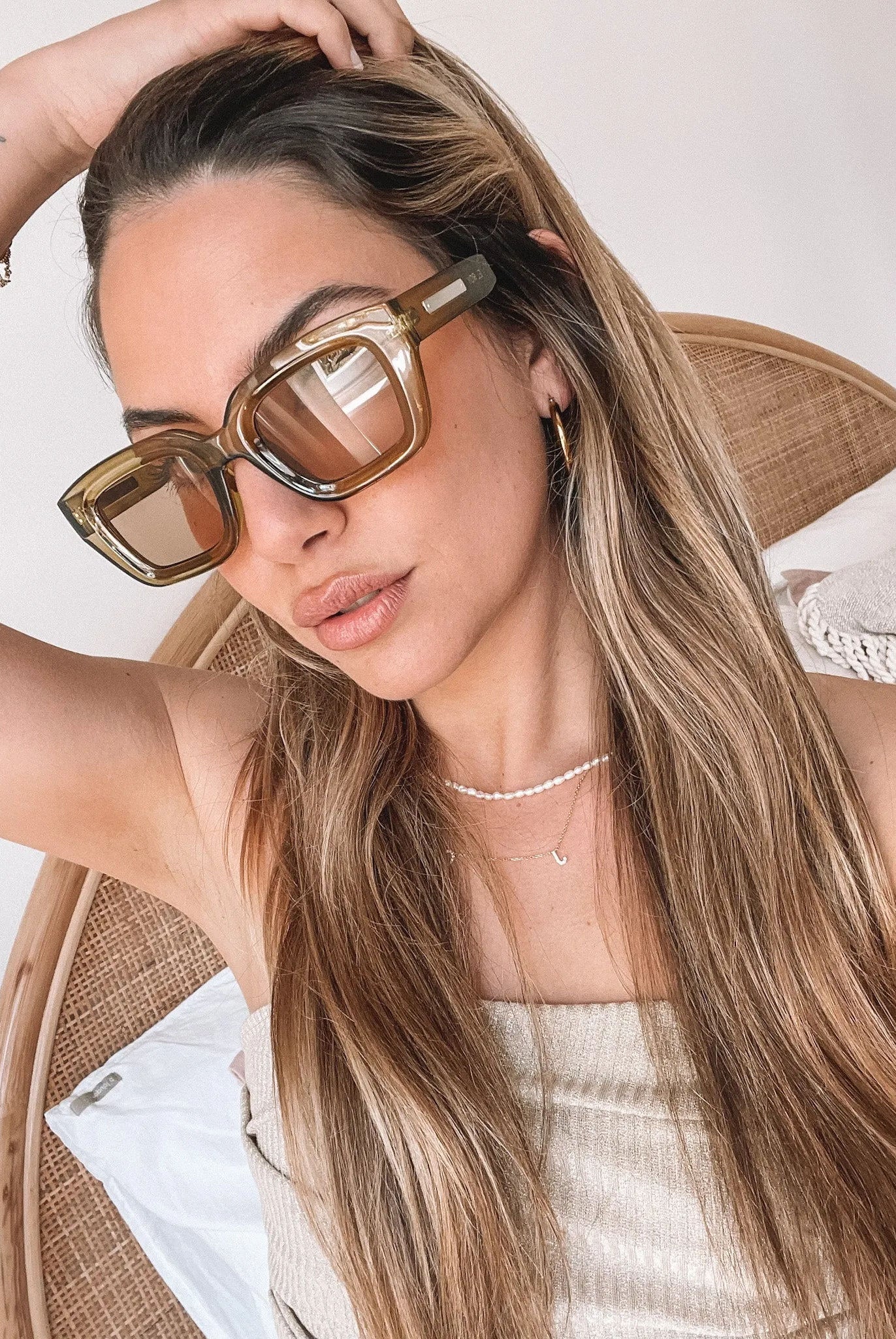A pair of sunglasses with olive green frames and pink lenses displayed on a surface.