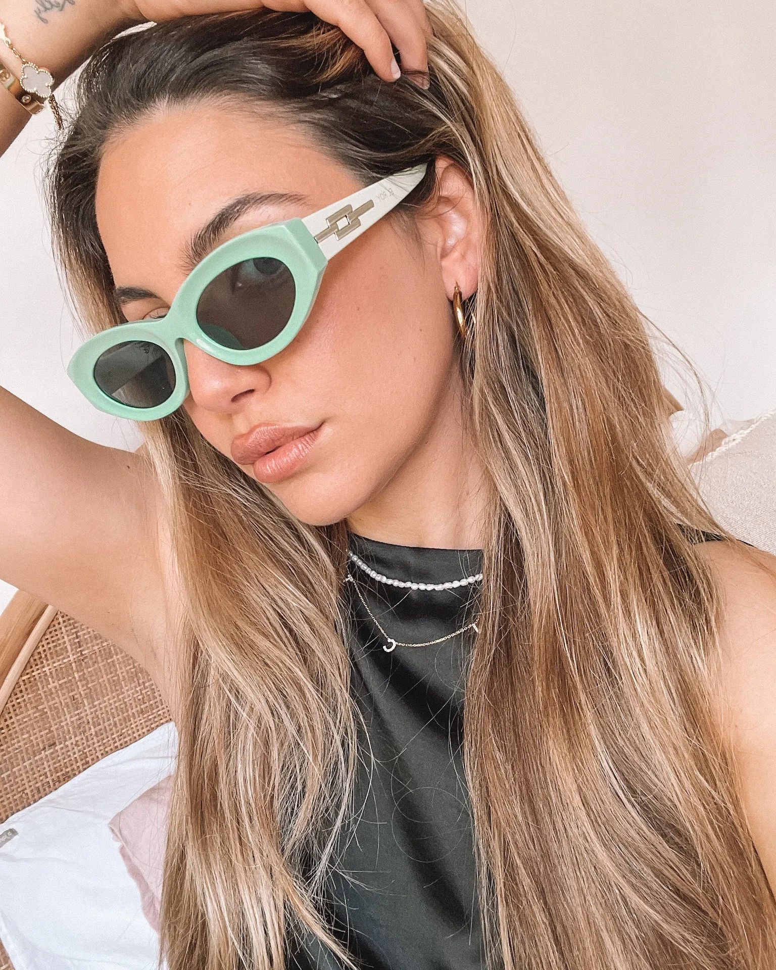 Close-up of a pair of bright green cat-eye sunglasses with dark lenses, placed on a smooth beige surface with a plain white background.