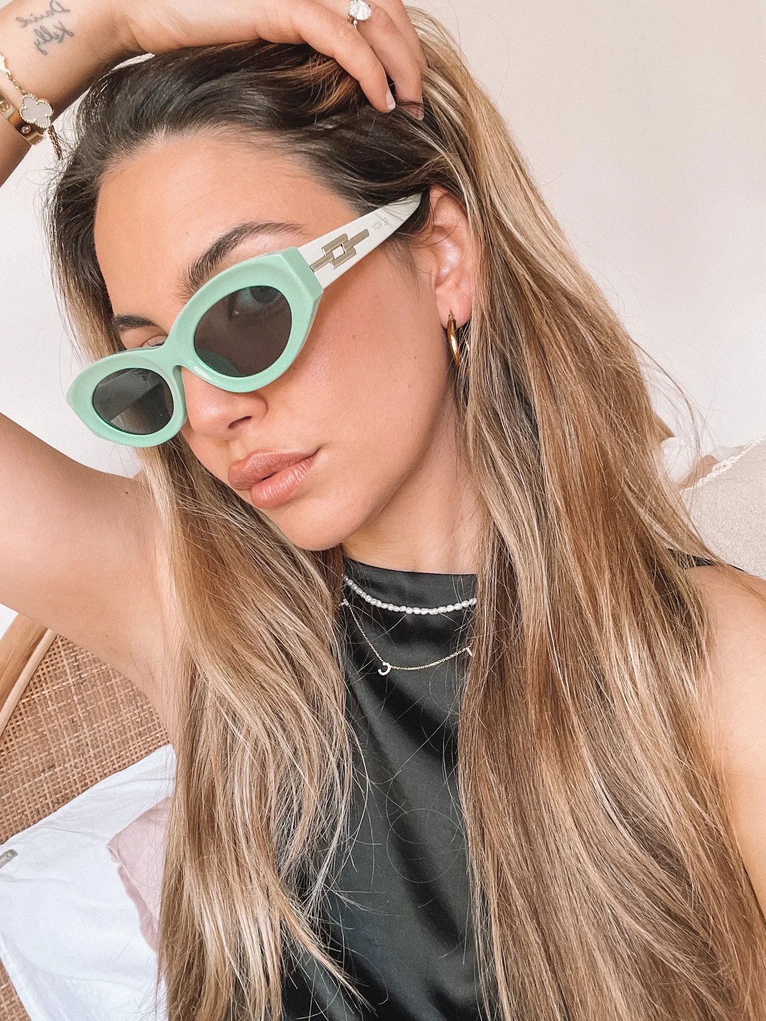 Close-up of a pair of bright green cat-eye sunglasses with dark lenses, placed on a smooth beige surface with a plain white background.