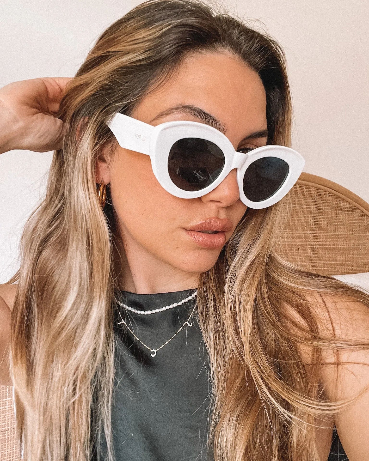 White cat-eye sunglasses with dark lenses displayed on a light beige marble surface against a plain white background.