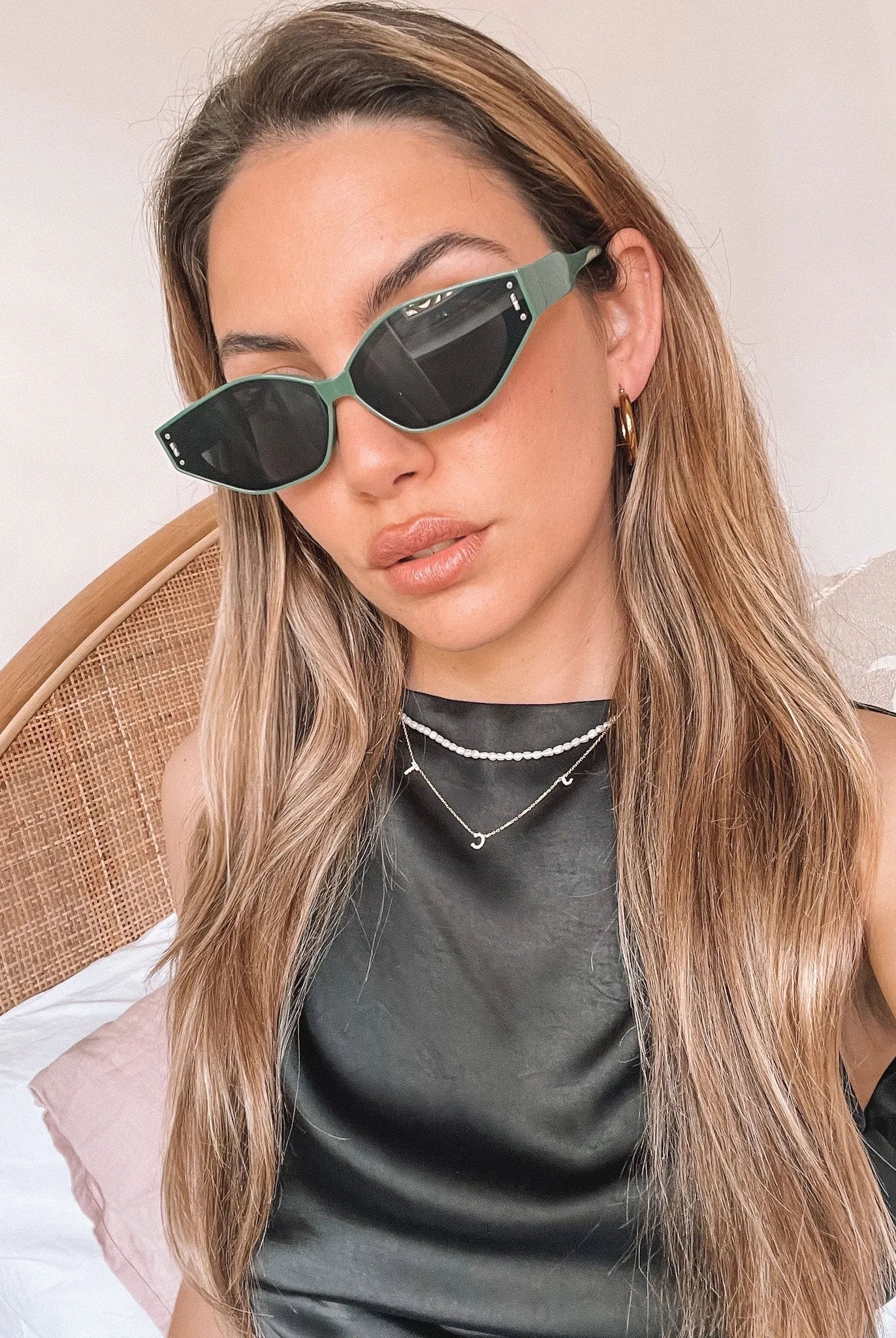 Green geometric-shaped sunglasses with dark lenses resting on a light marble surface against a plain white background.