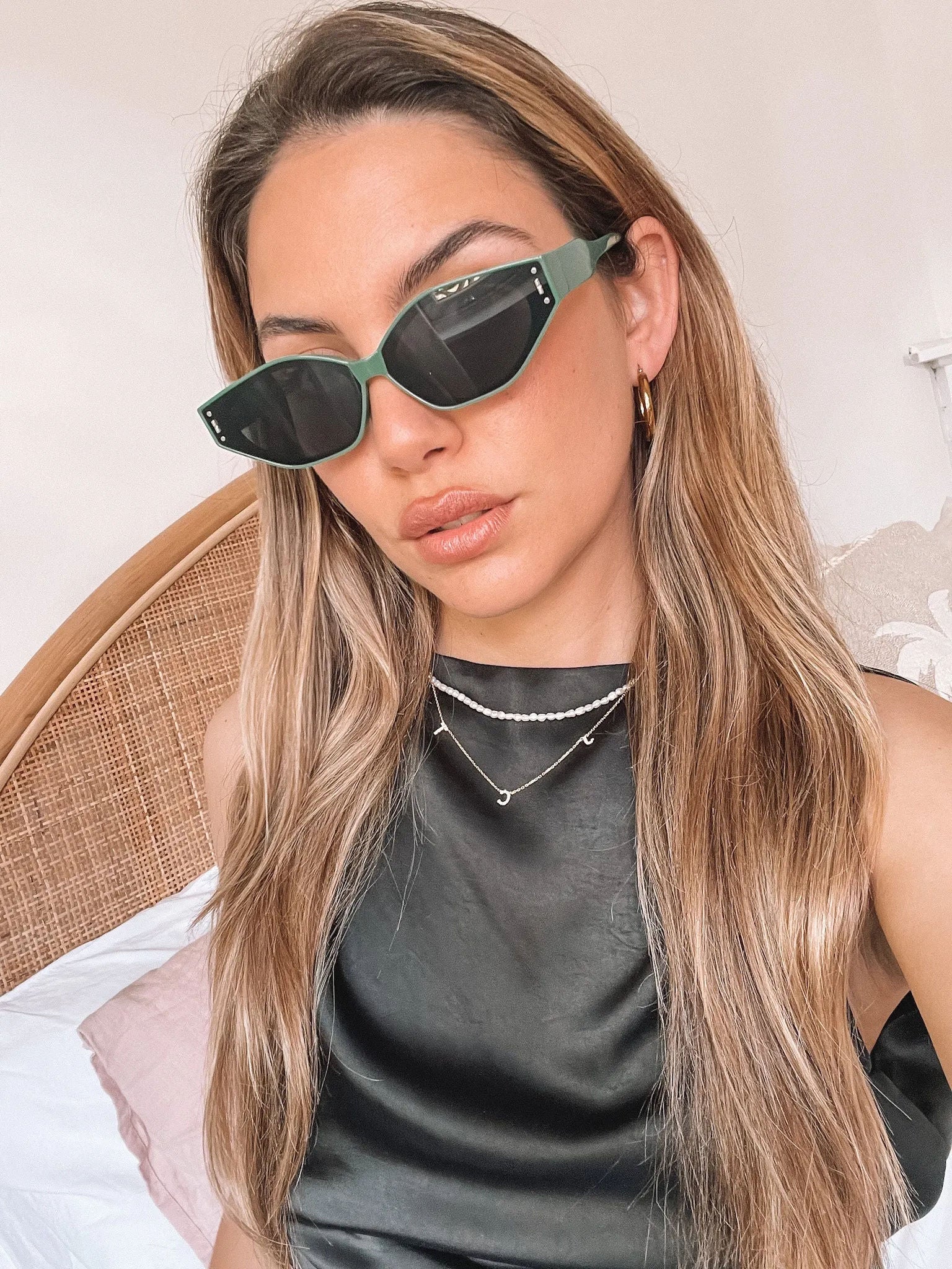 Green geometric-shaped sunglasses with dark lenses resting on a light marble surface against a plain white background.