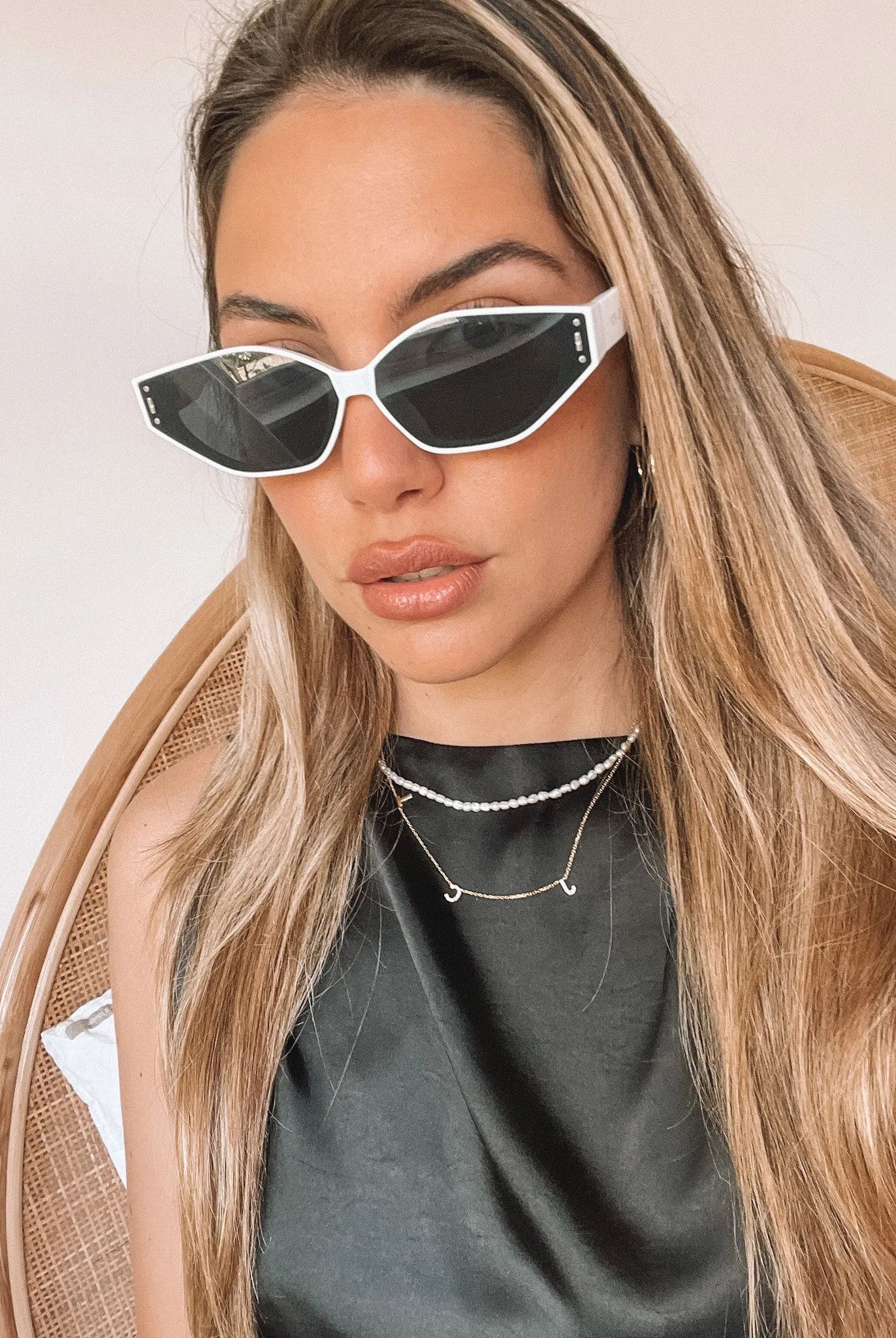 White geometric-shaped sunglasses with dark lenses resting on a light marble surface against a plain white background.