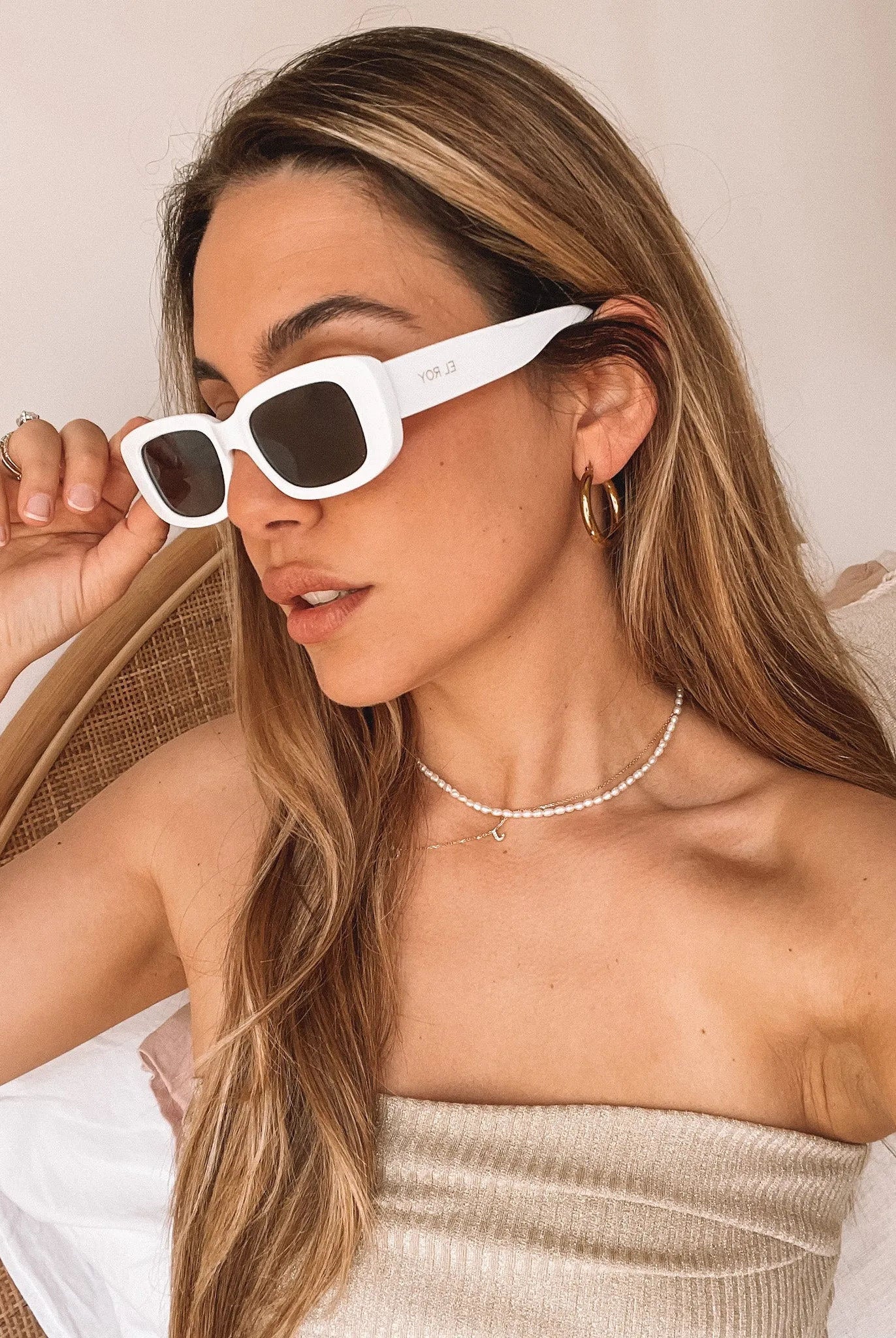 A pair of white-framed sunglasses displayed against a neutral background.