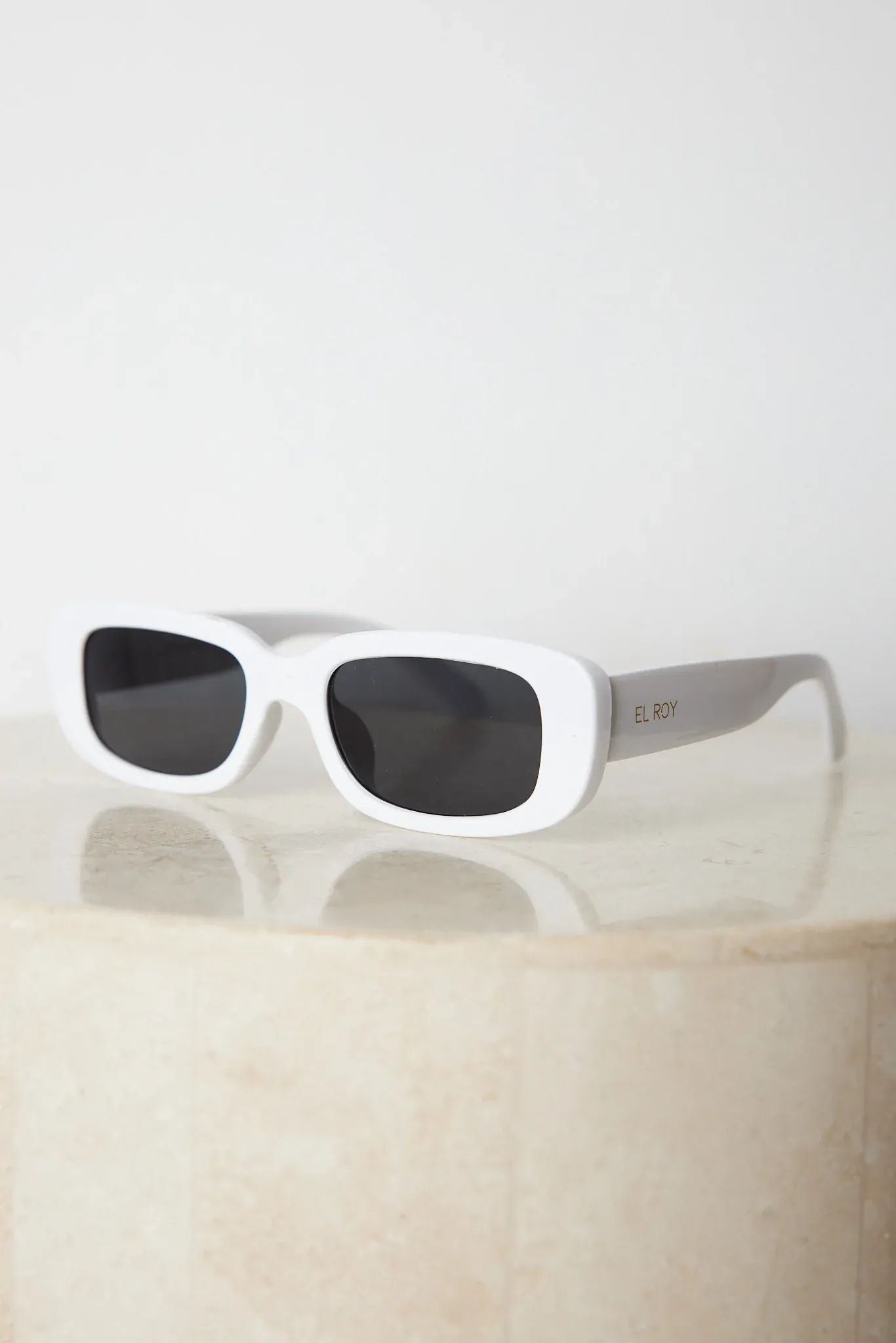 A pair of white-framed sunglasses displayed against a neutral background.