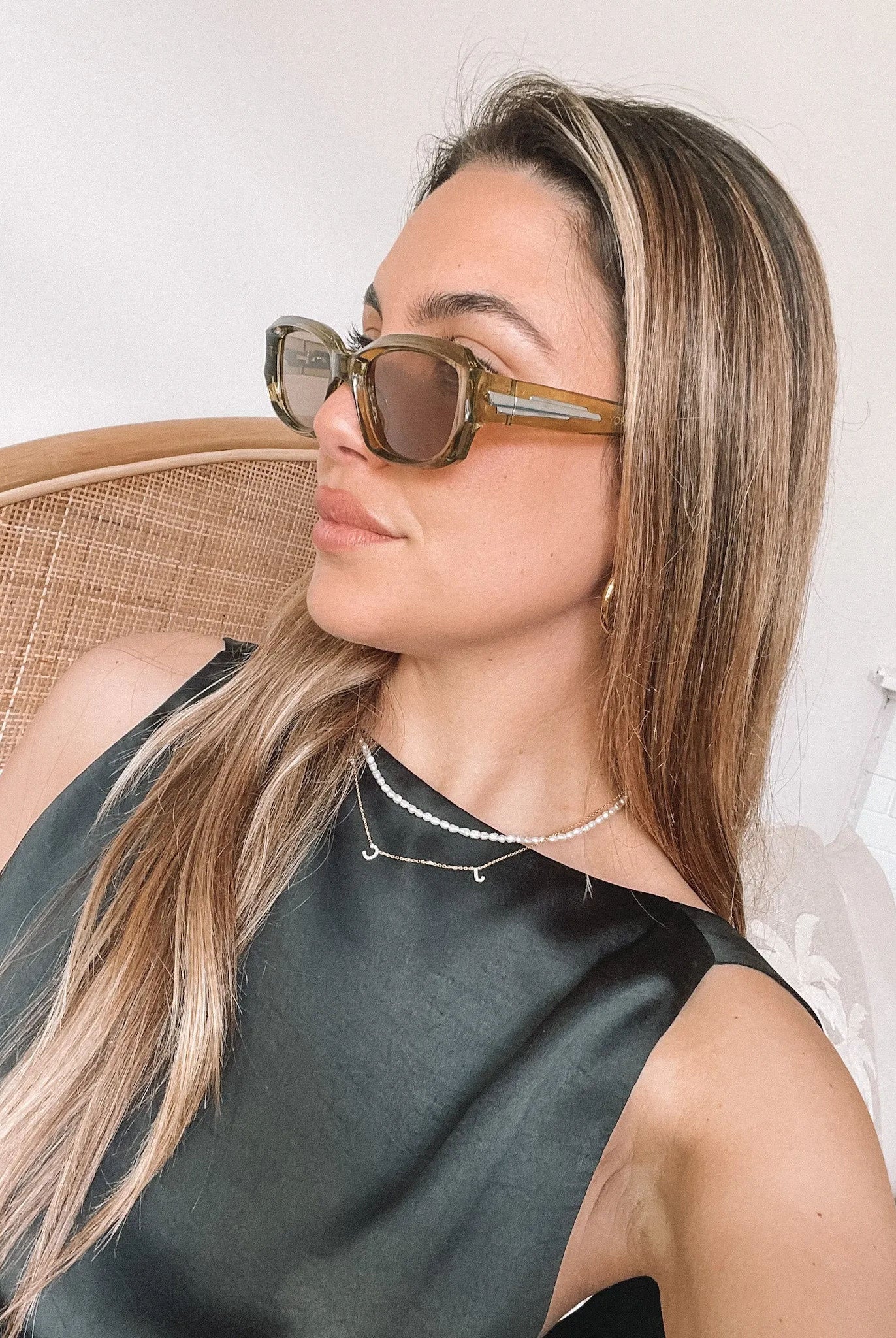 Rectangular sunglasses with translucent olive green frames and brown tinted lenses, displayed on a light beige stone surface against a plain white background.
