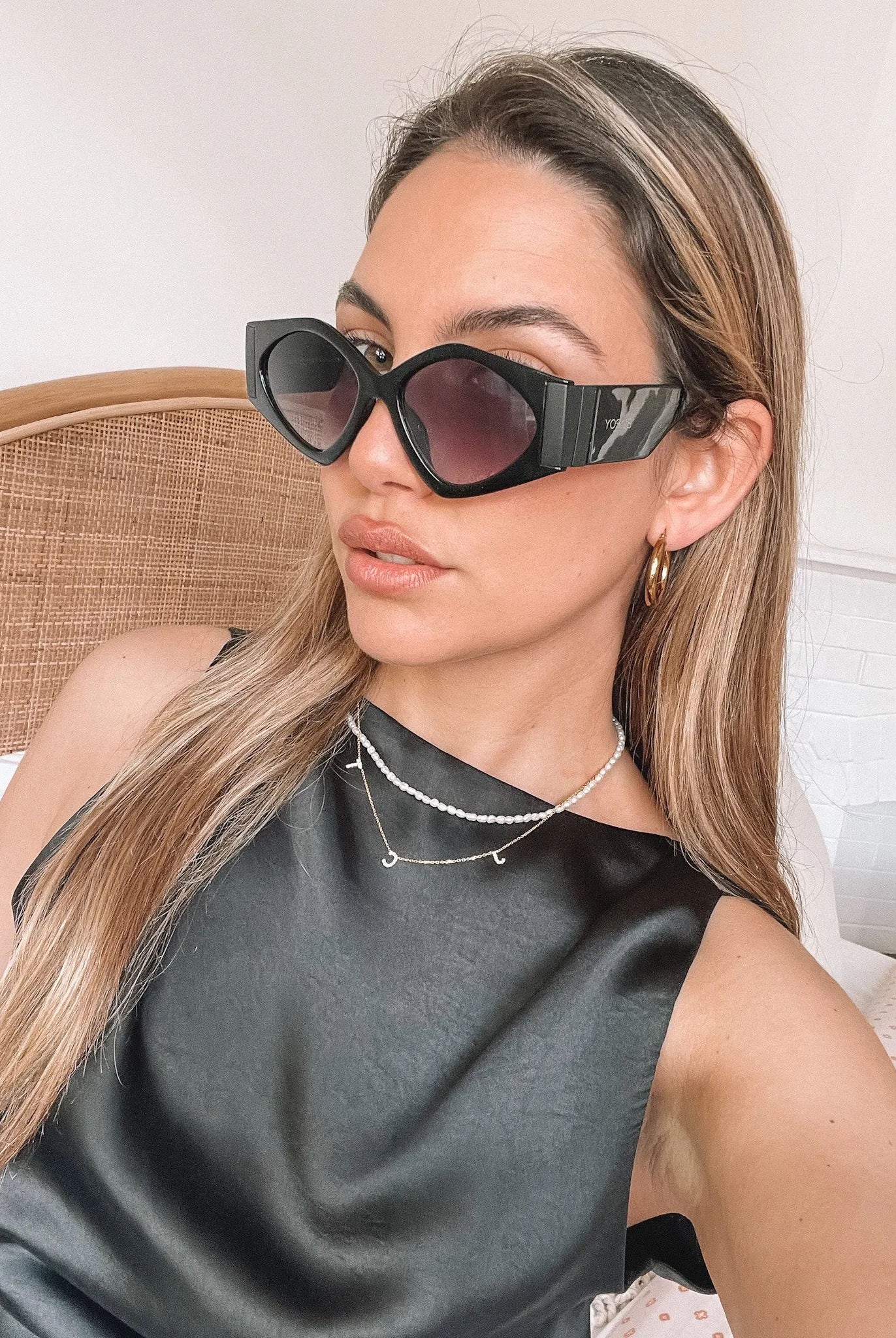 Black cat-eye sunglasses with thick frames and dark tinted lenses, displayed on a light beige surface against a plain white background.
