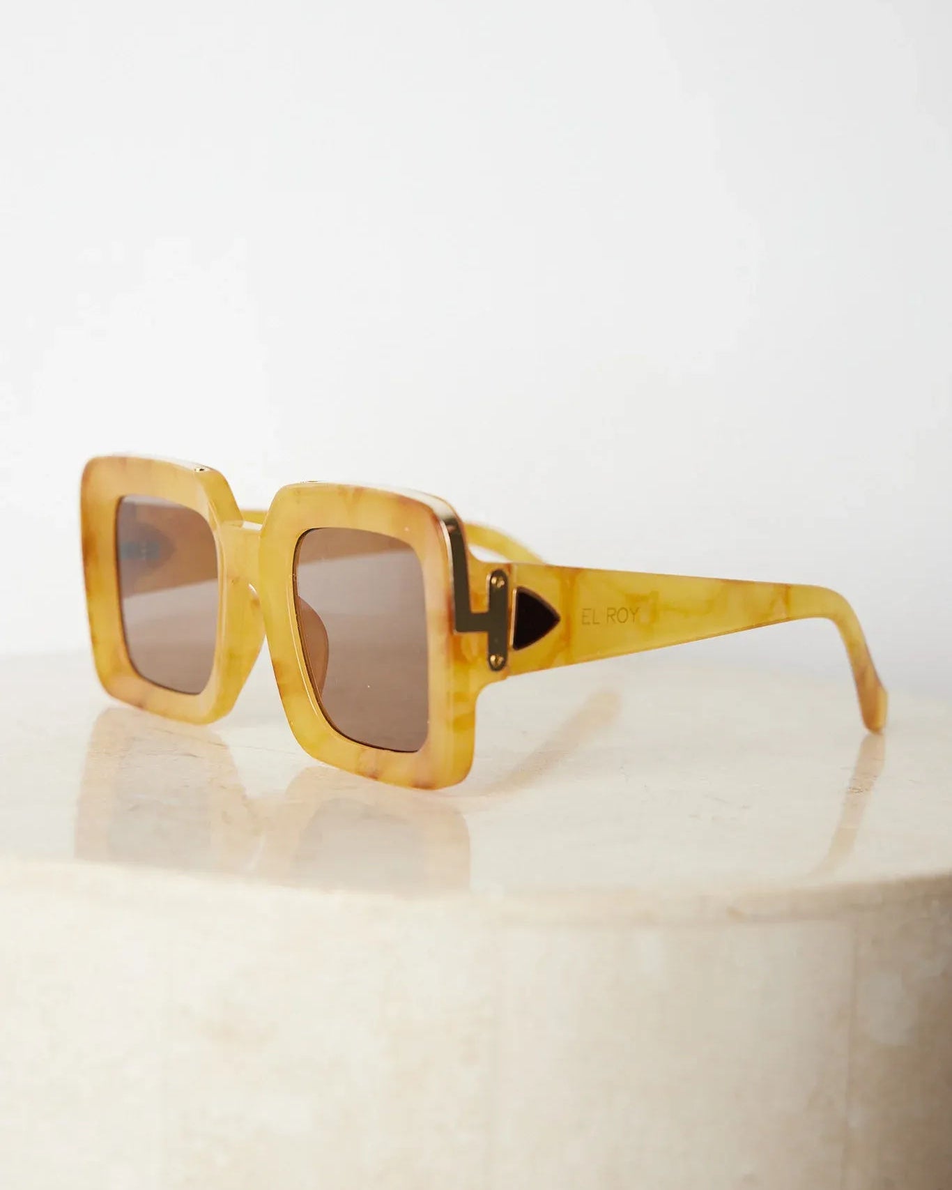 A pair of sunglasses with a tan frame displayed on a surface.