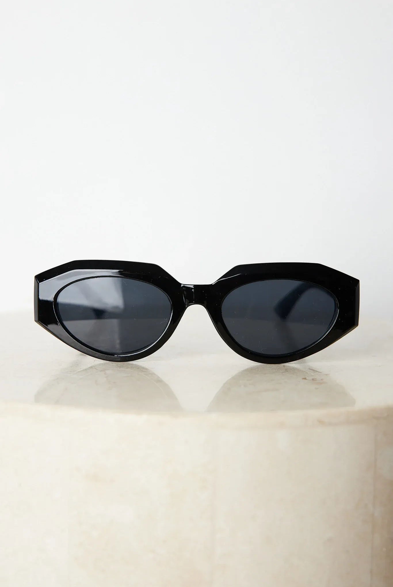 A pair of black sunglasses displayed against a neutral background.