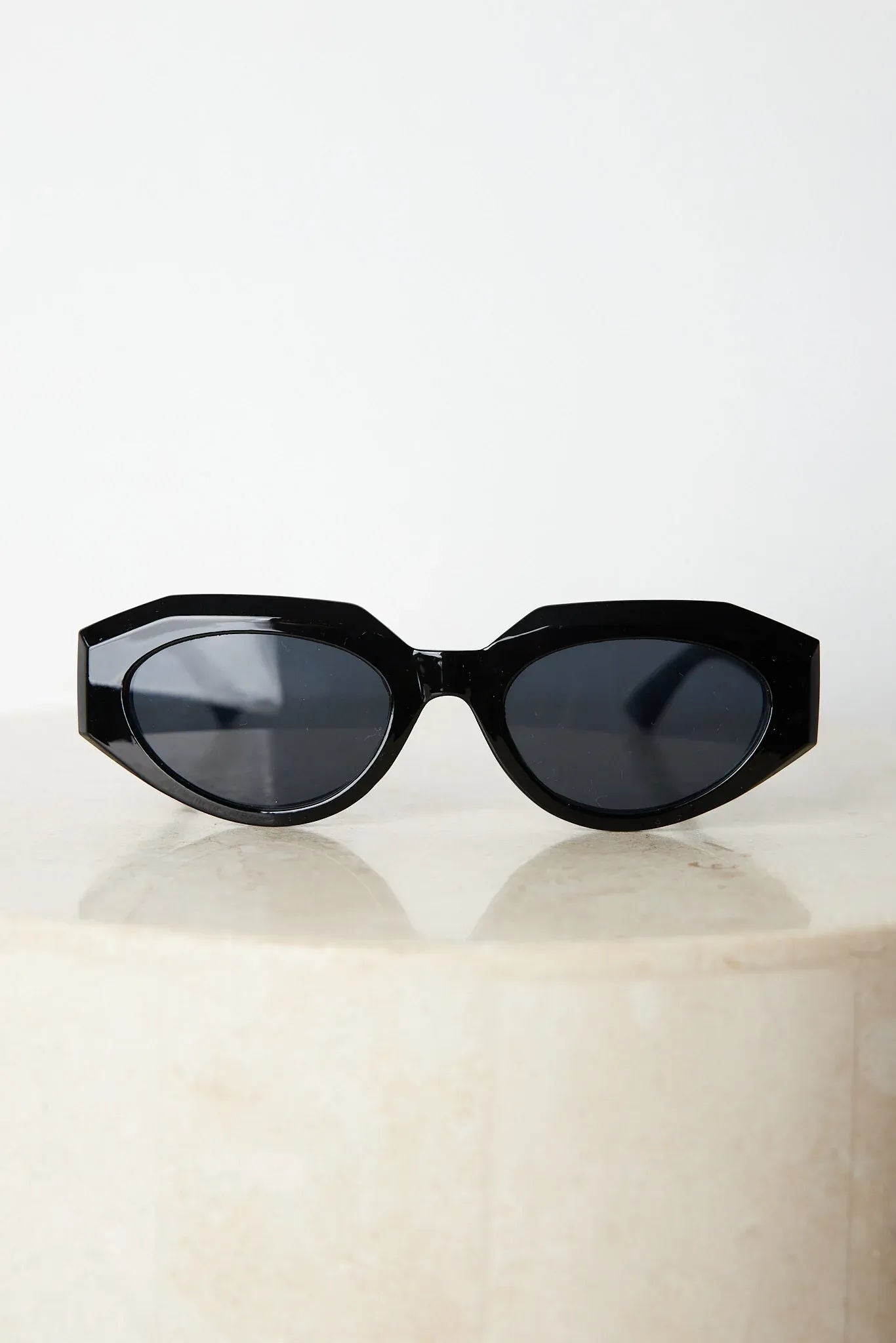 A pair of black sunglasses displayed against a neutral background.