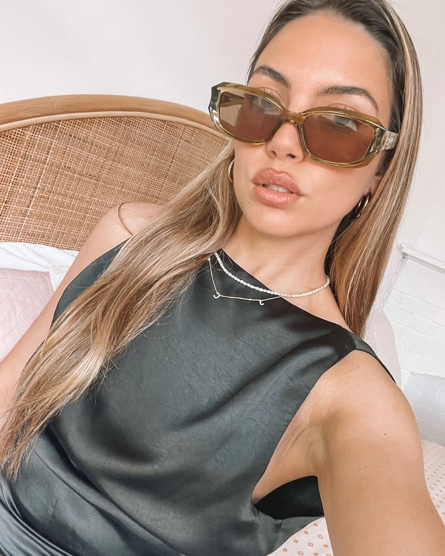 Rectangular sunglasses with translucent olive green frames and brown tinted lenses, displayed on a light beige stone surface against a plain white background.