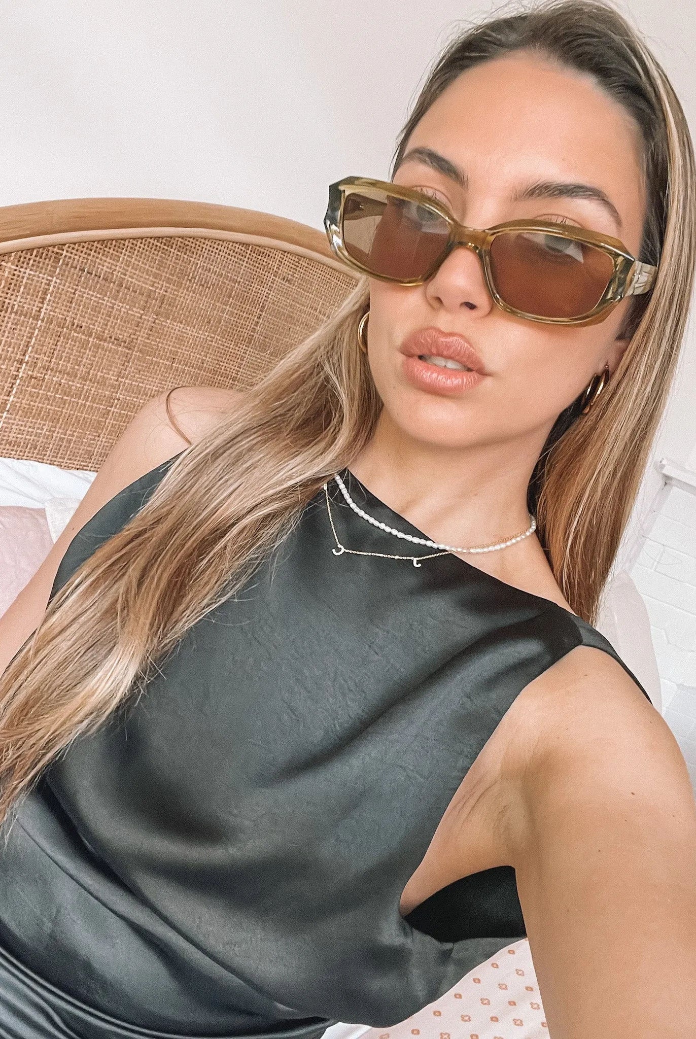 Rectangular sunglasses with translucent olive green frames and brown tinted lenses, displayed on a light beige stone surface against a plain white background.