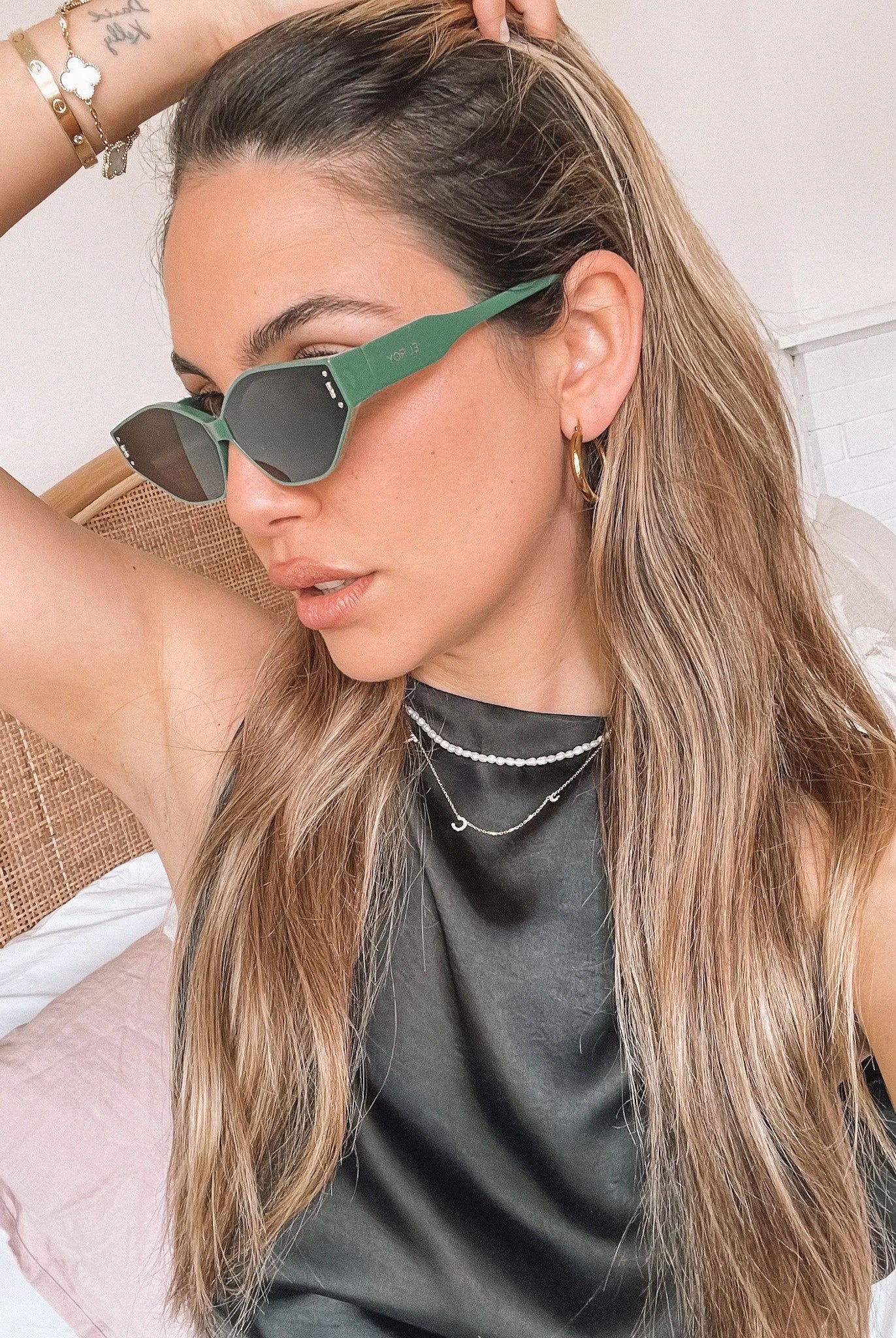 Green geometric-shaped sunglasses with dark lenses resting on a light marble surface against a plain white background.