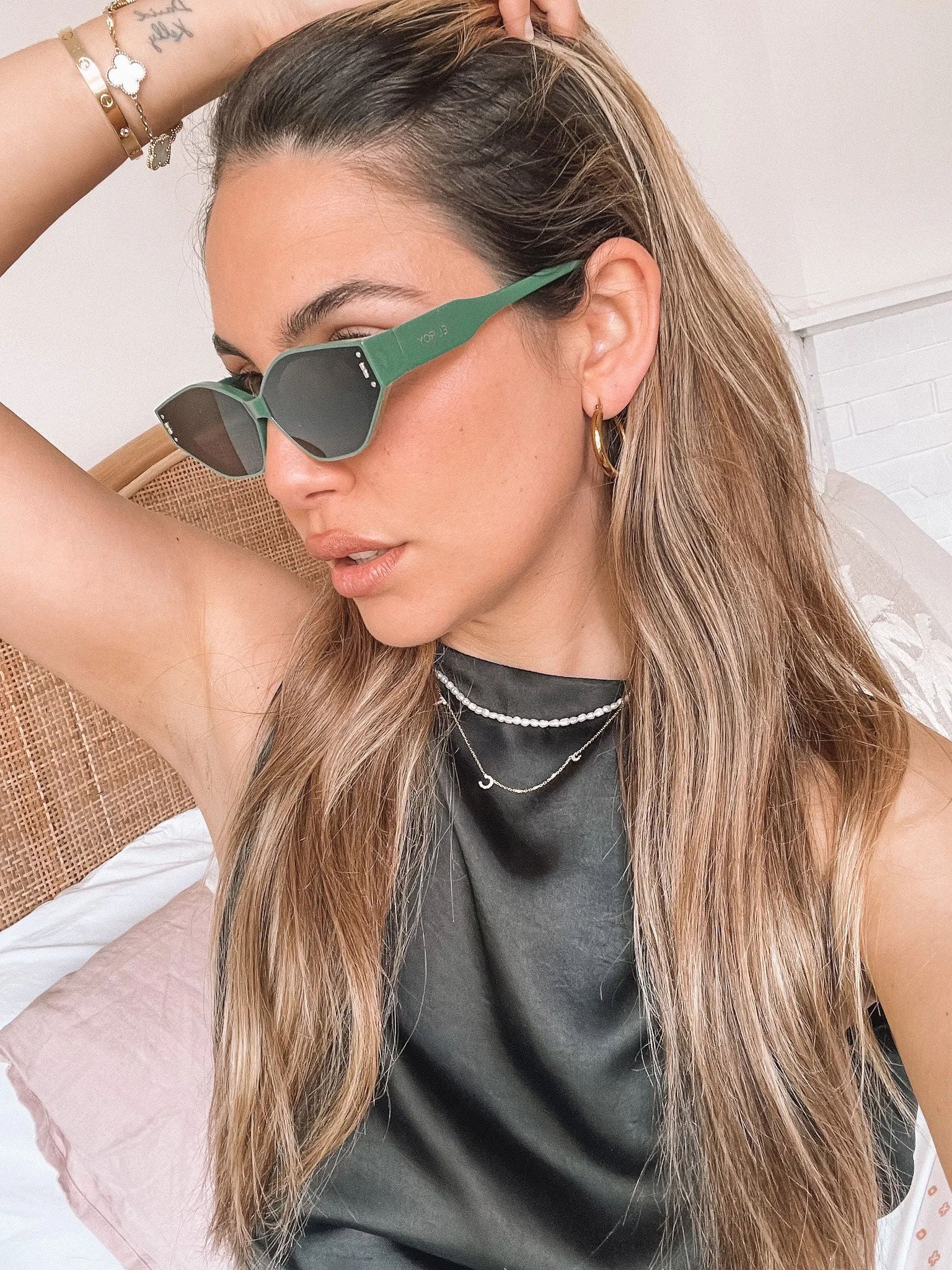Green geometric-shaped sunglasses with dark lenses resting on a light marble surface against a plain white background.